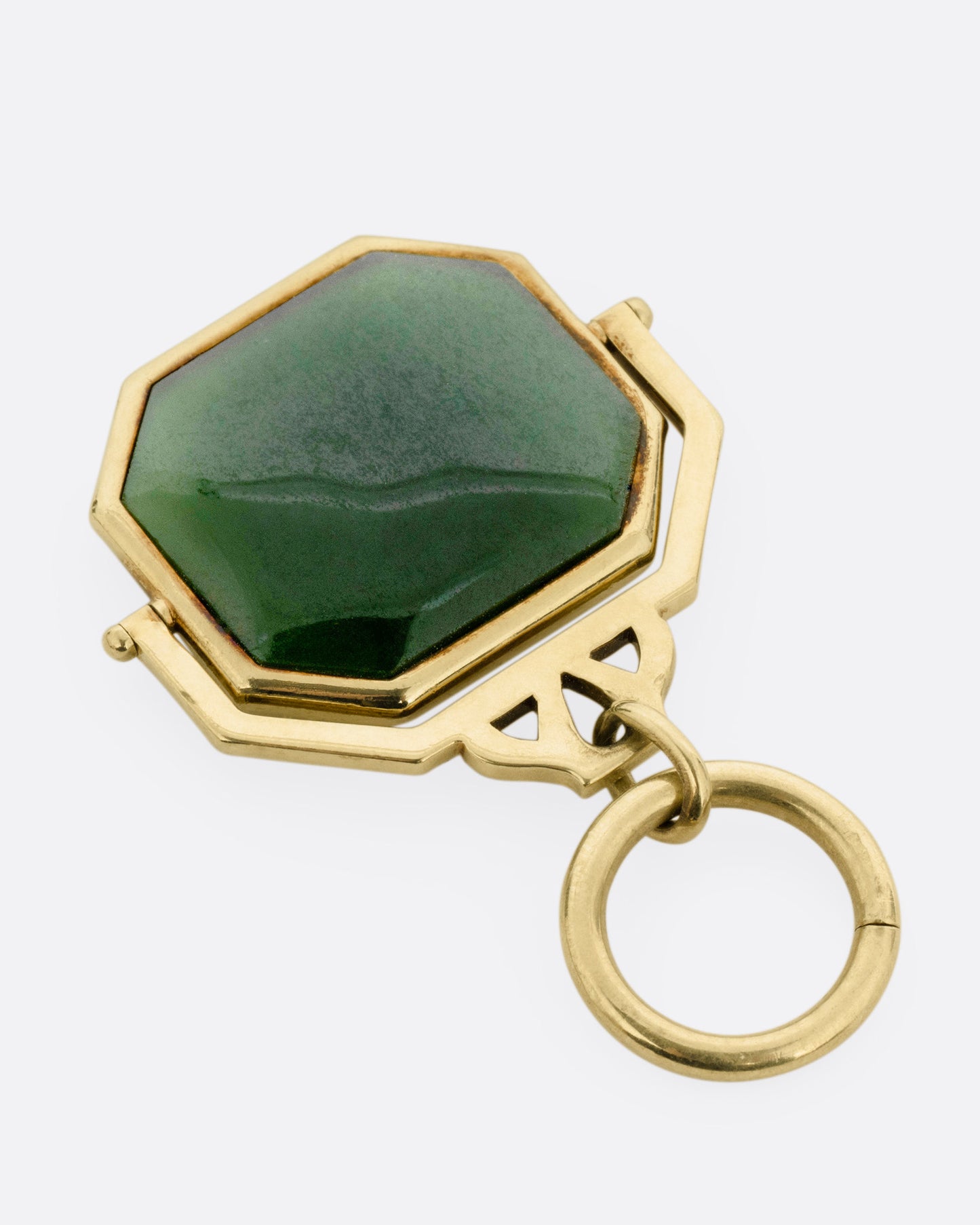 A yellow gold pendant with a spinning swath of jade, shown from the back.