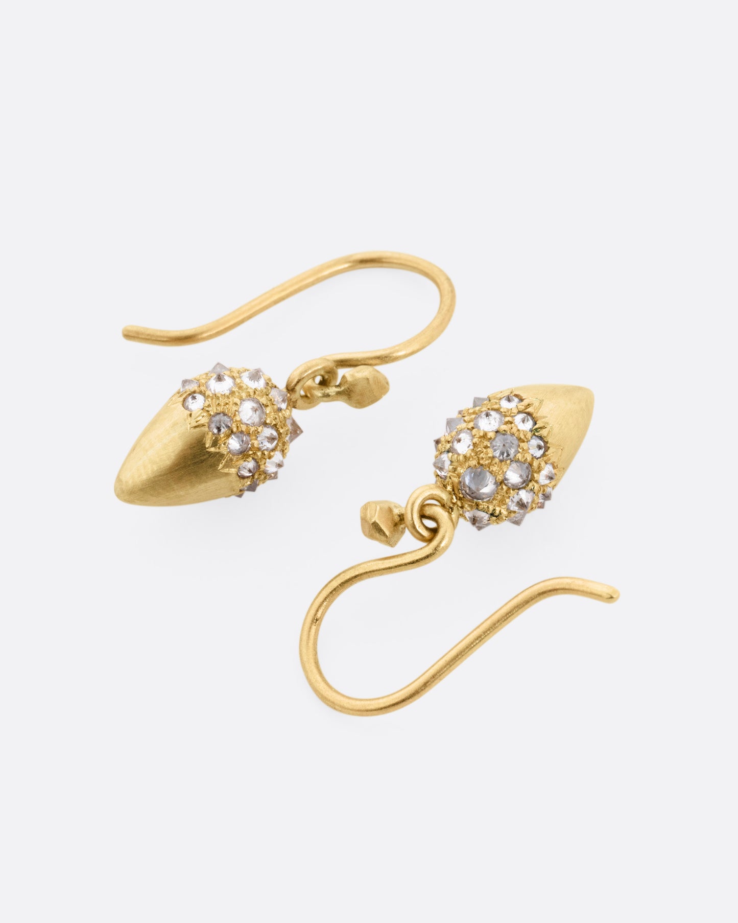 A pair of yellow gold drop earrings with reverse set diamonds on the top half. Shown lying flat.