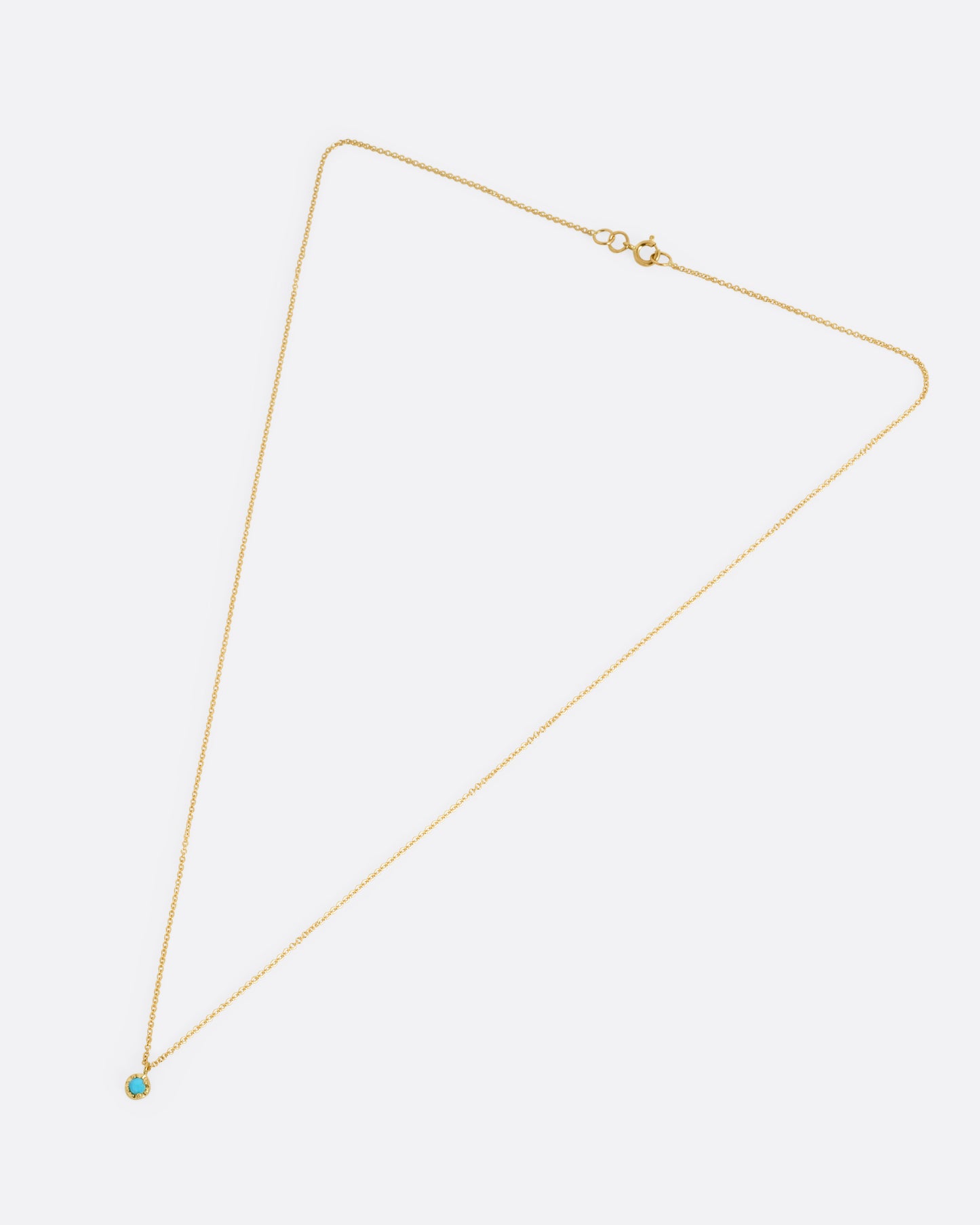 A yellow gold cable chain necklace with a prong set turquoise, shown from the front.