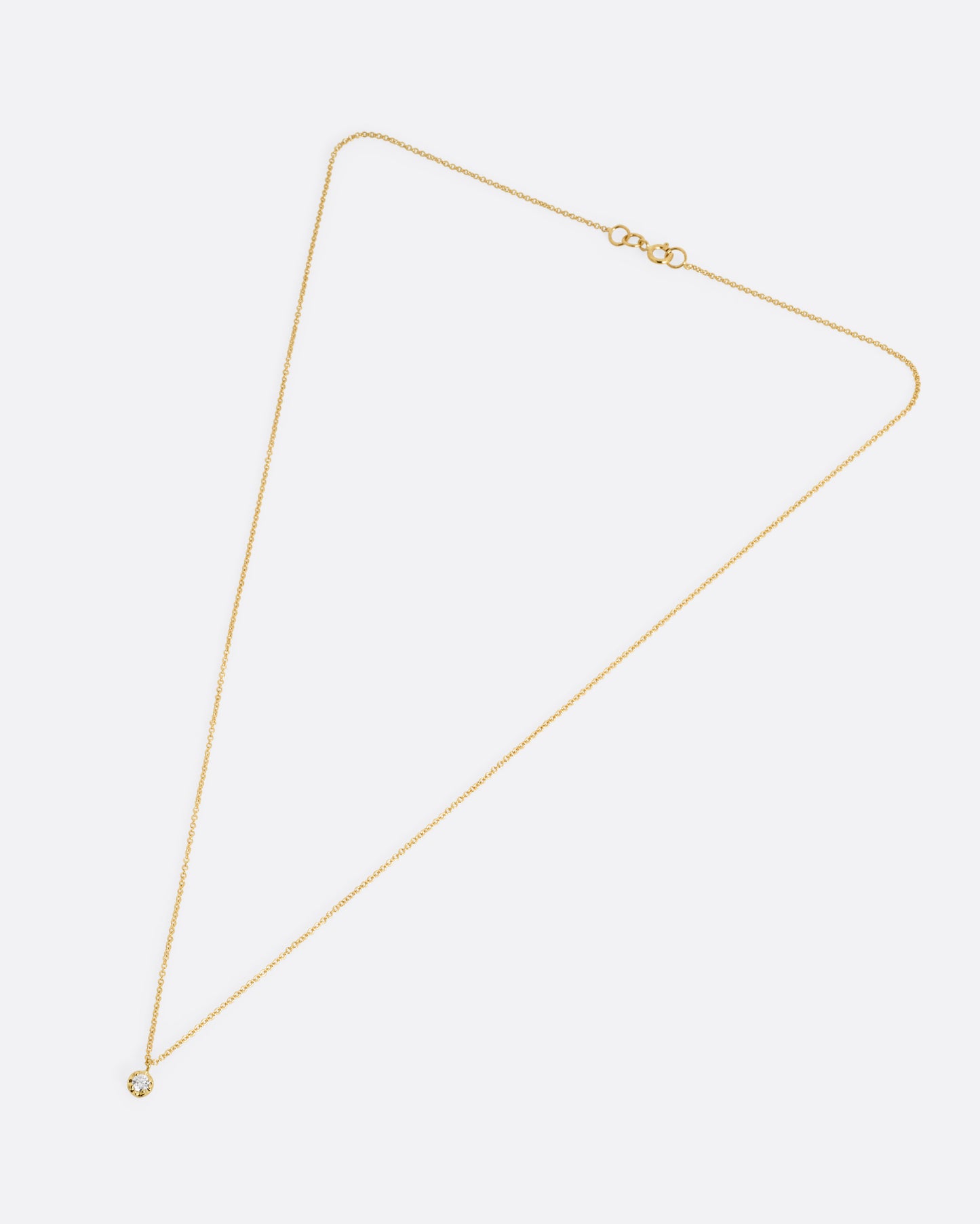 A yellow gold cable chain necklace with a prong set white diamond, shown from the front.