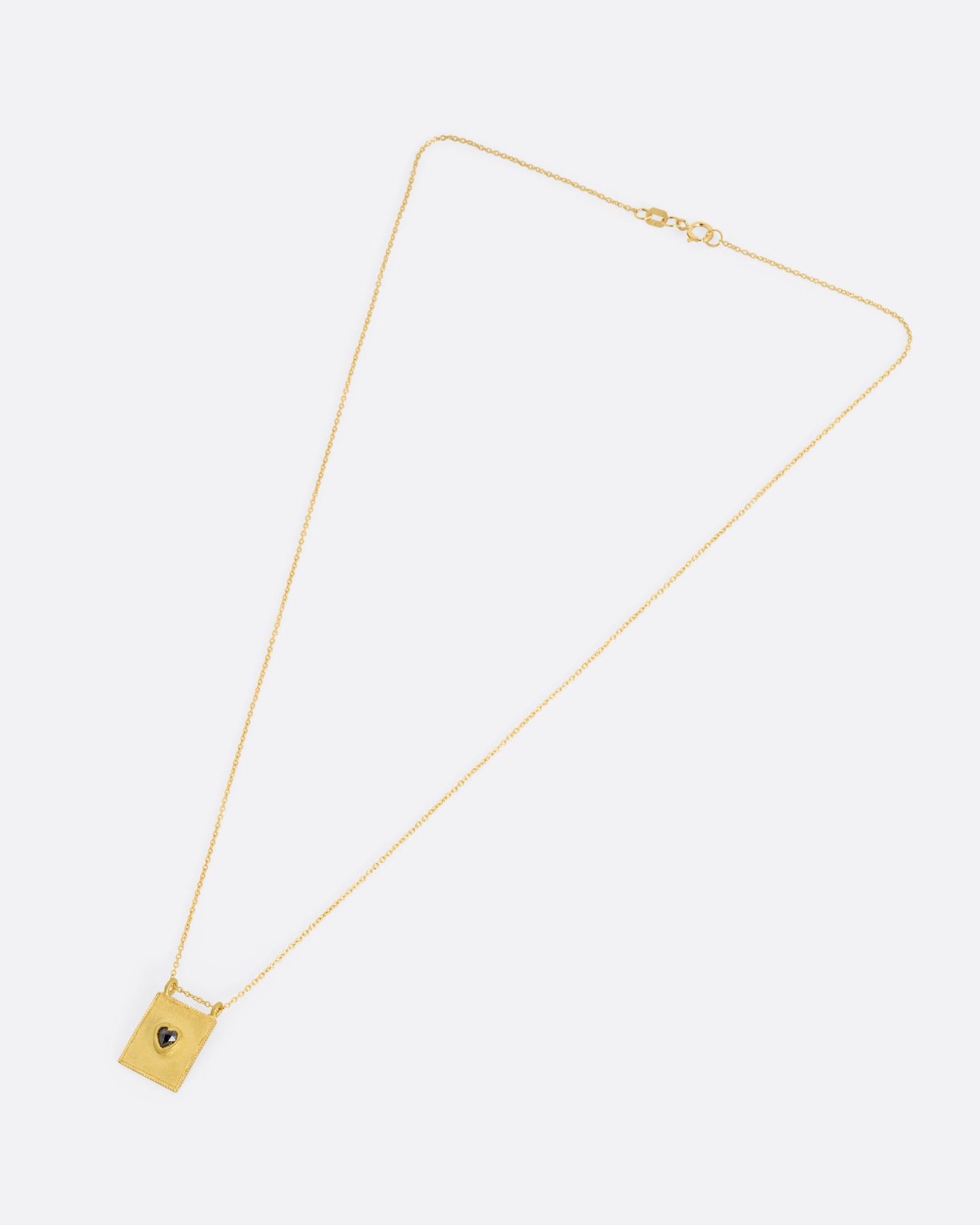 A yellow gold pendant necklace with a heart shaped salt and pepper diamond in a rectangular gold frame, with a double bail. Shown from the front.