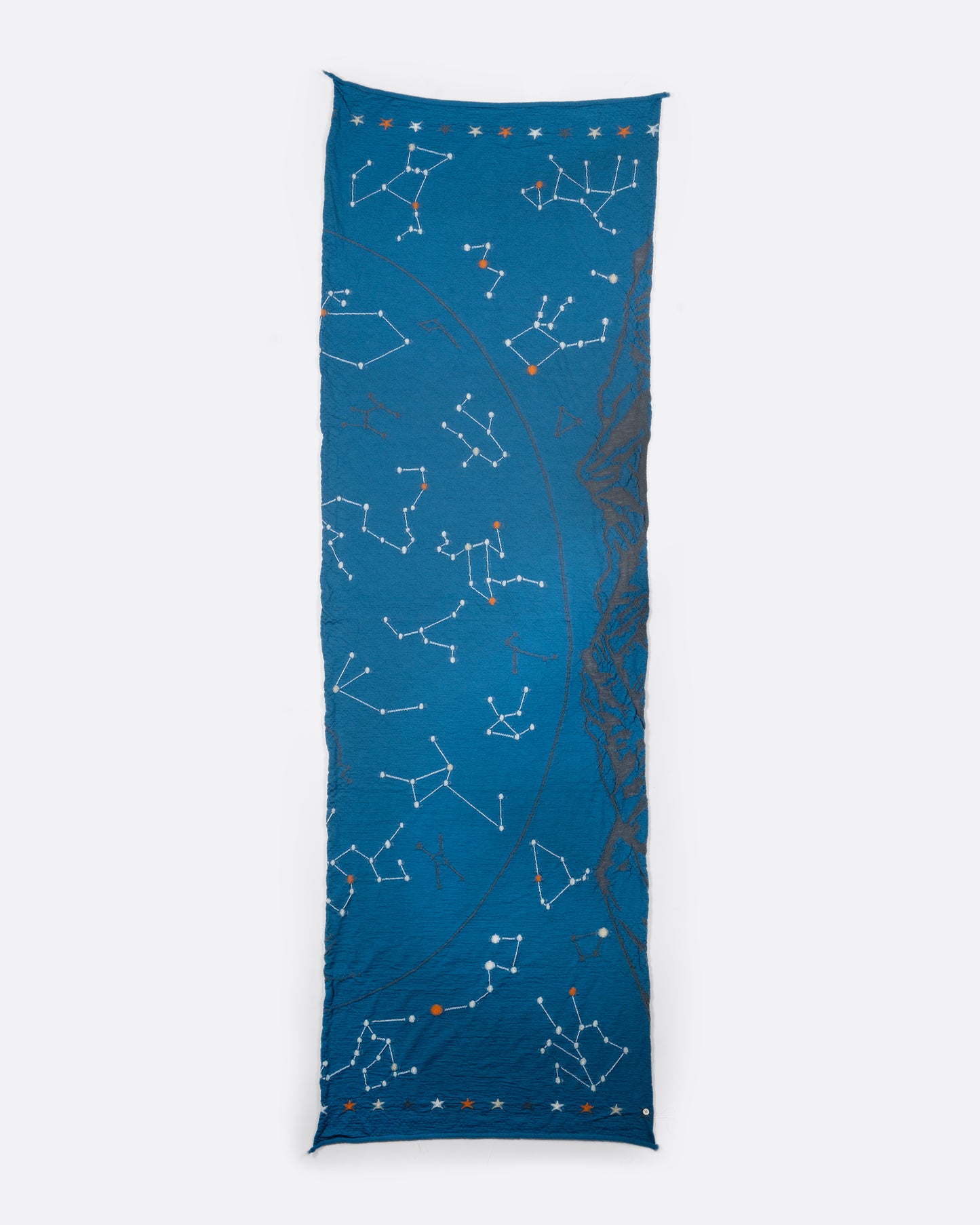 A light blue scarf with constellations novelty knit. View laying flat.