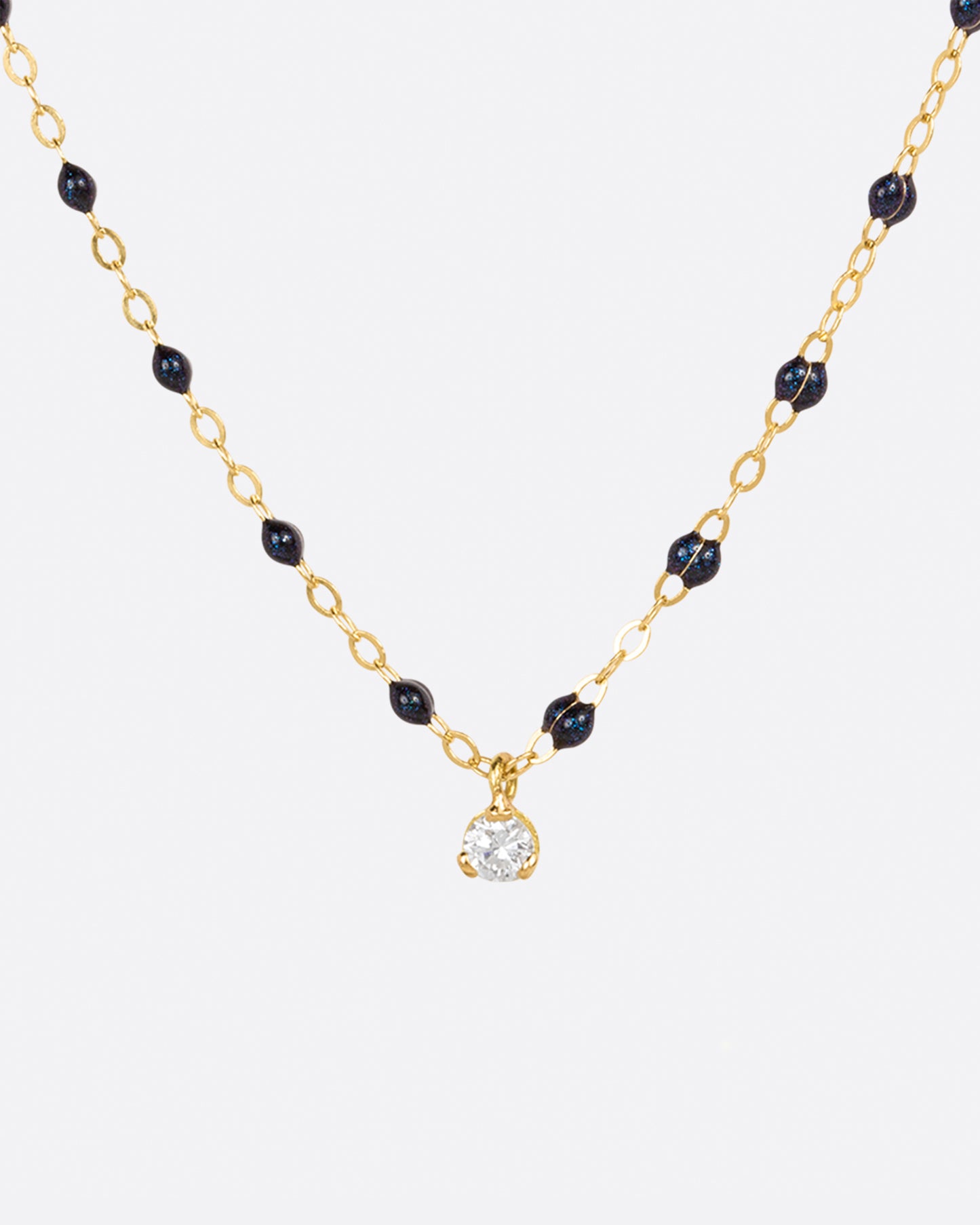 A classic Gigi Clozeau necklace with midnight blue resin beads and a single diamond charm.