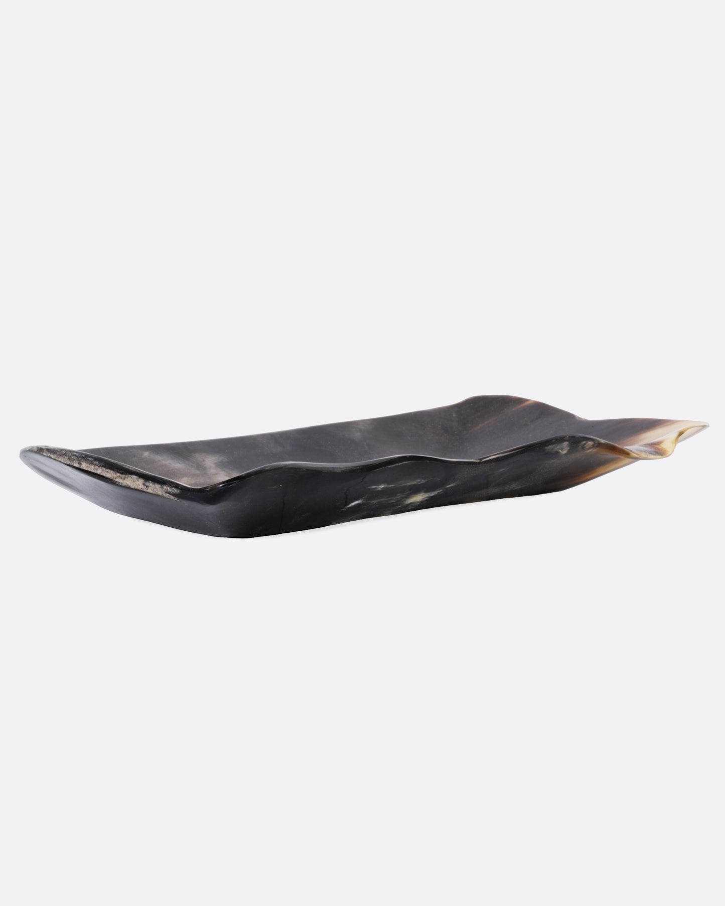 A rectangular buffalo horn tray with a natural edge and swirling deep brown and cream coloring, shown from the side.