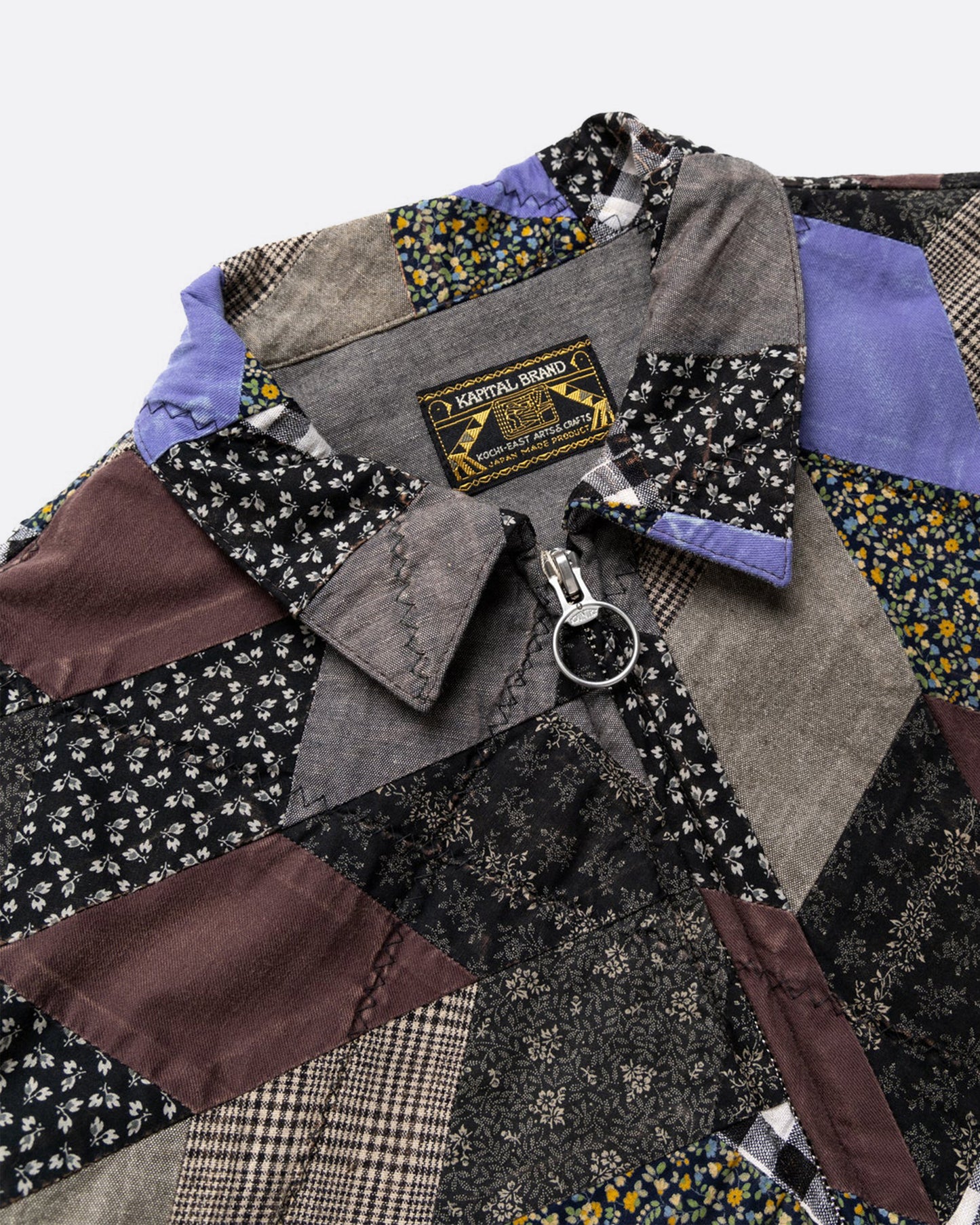 A cropped jacket with an arrow shaped patchwork and zip front. Shown close up from the front.