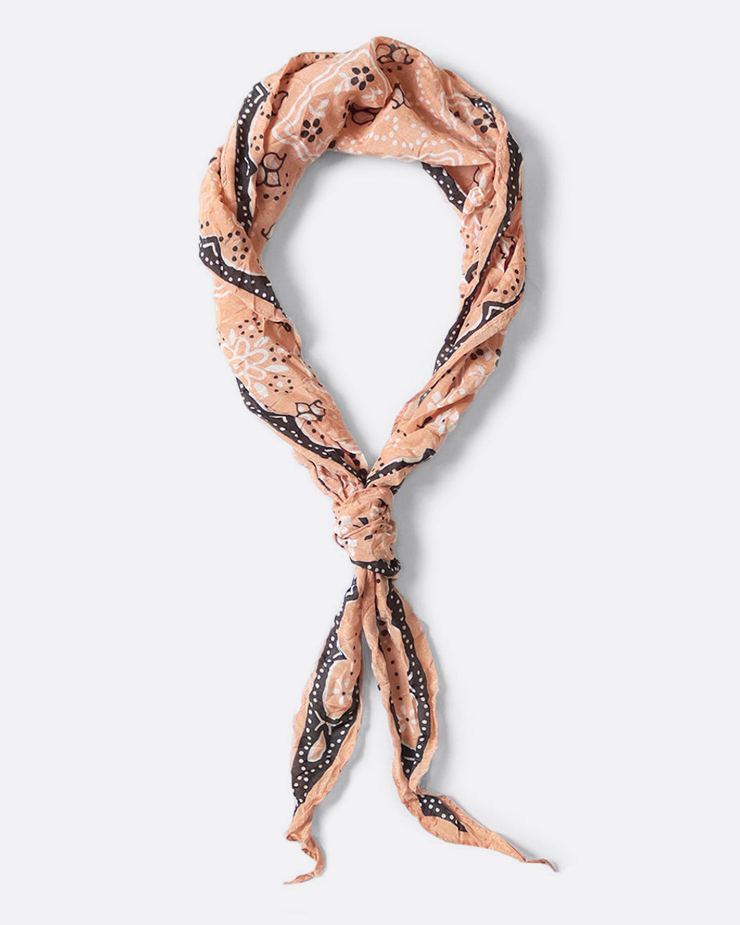 A peach colored diamond-shaped neckerchief with a paisley motif. Shown tied in a loop lying flat.