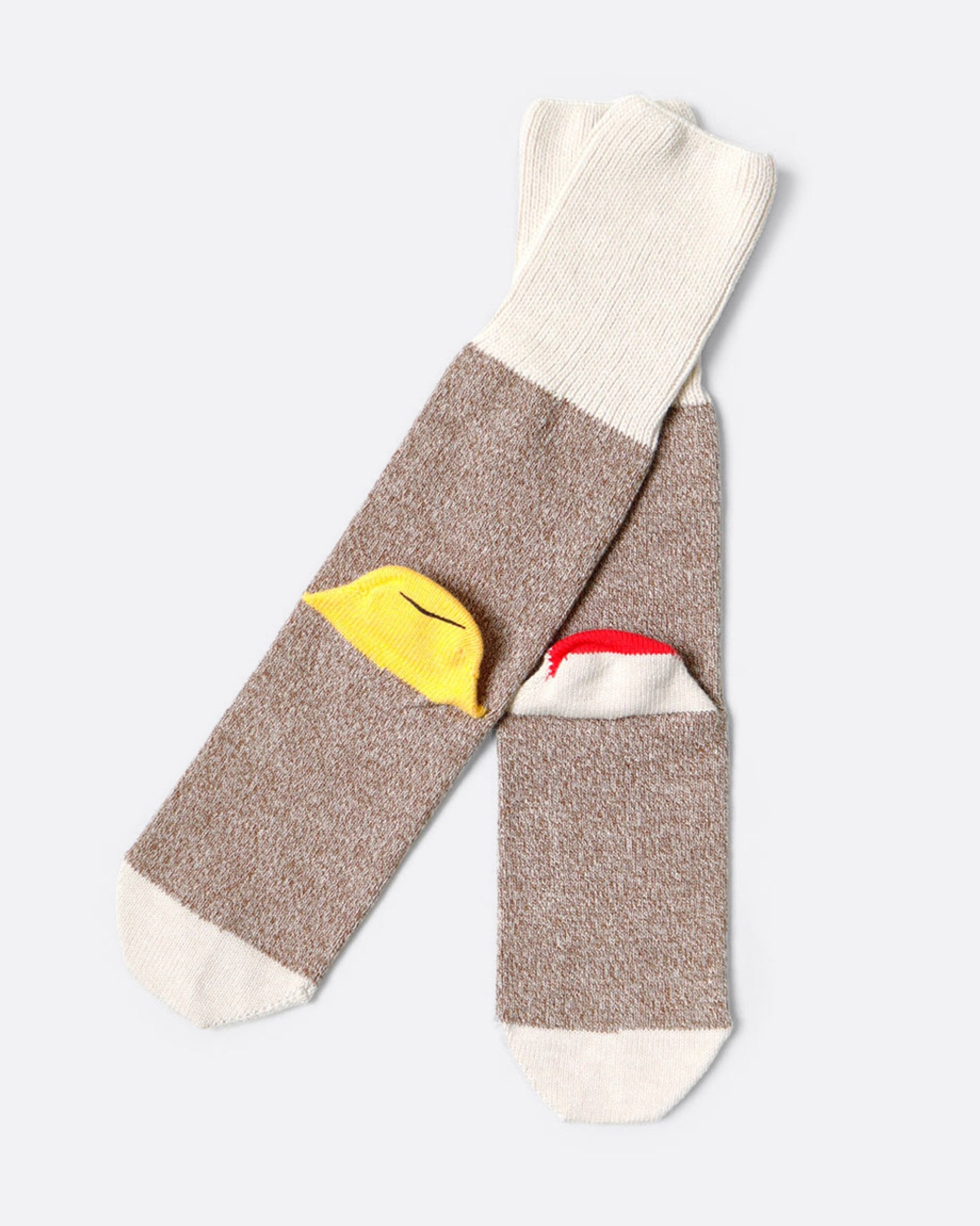 A pair of melange socks with a smiley on one heel and the beginnings of a 'sock monkey' face on the other. Shown from the back.