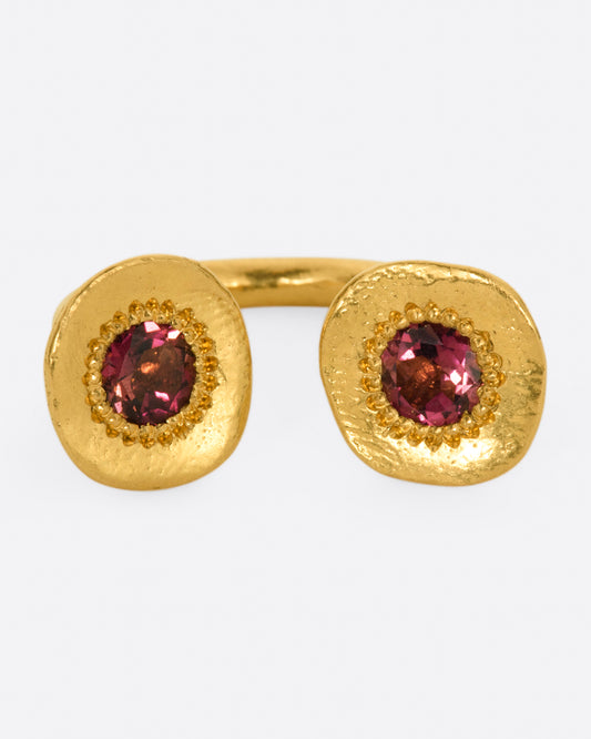 A high karat gold open ring with a large organic shaped disc on each end with a rosey pink tourmaline at its center. 