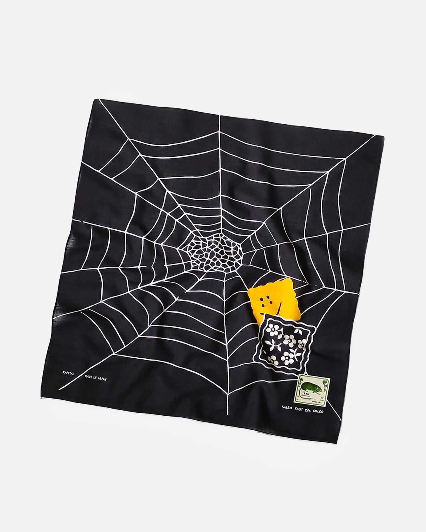 black bandana with a white spider web and two colorful patch graphics in one corner, shown from the front.
