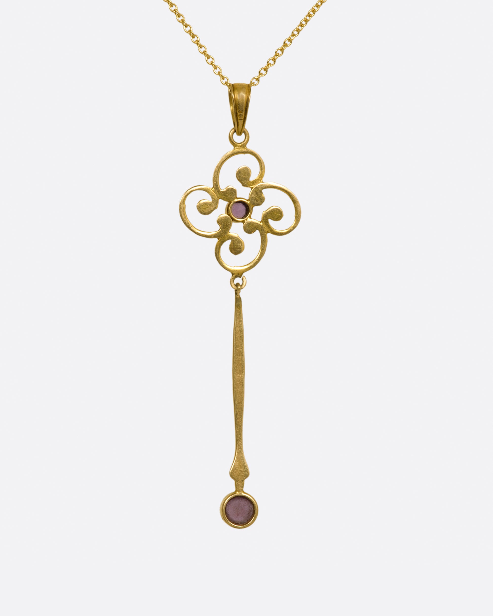A contemporary yellow gold chain necklace with a vintage yellow gold pendant. The pendant has a flower-like design at the top with with a long bar hanging from it, and a round amethyst at the bottom.