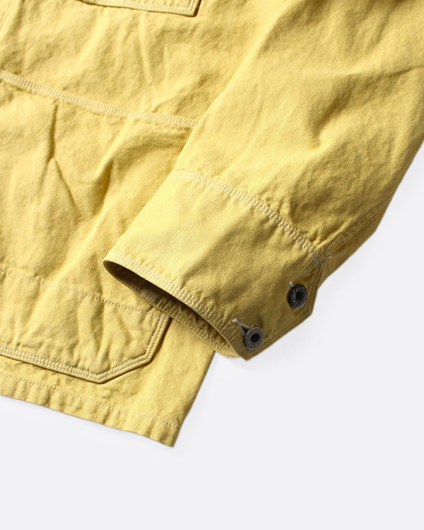 A close up of the sleeve of a yellow canvas chore coat.