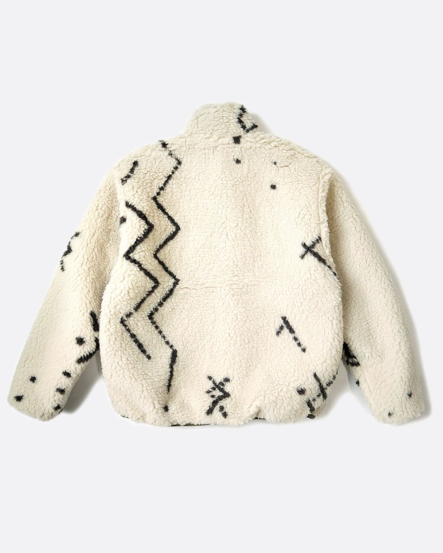 A reverisble jacket with white Beni Ourain patterned fleece on one side and a green nylon shell on the other, shown laying flat on the back of the fleece side.