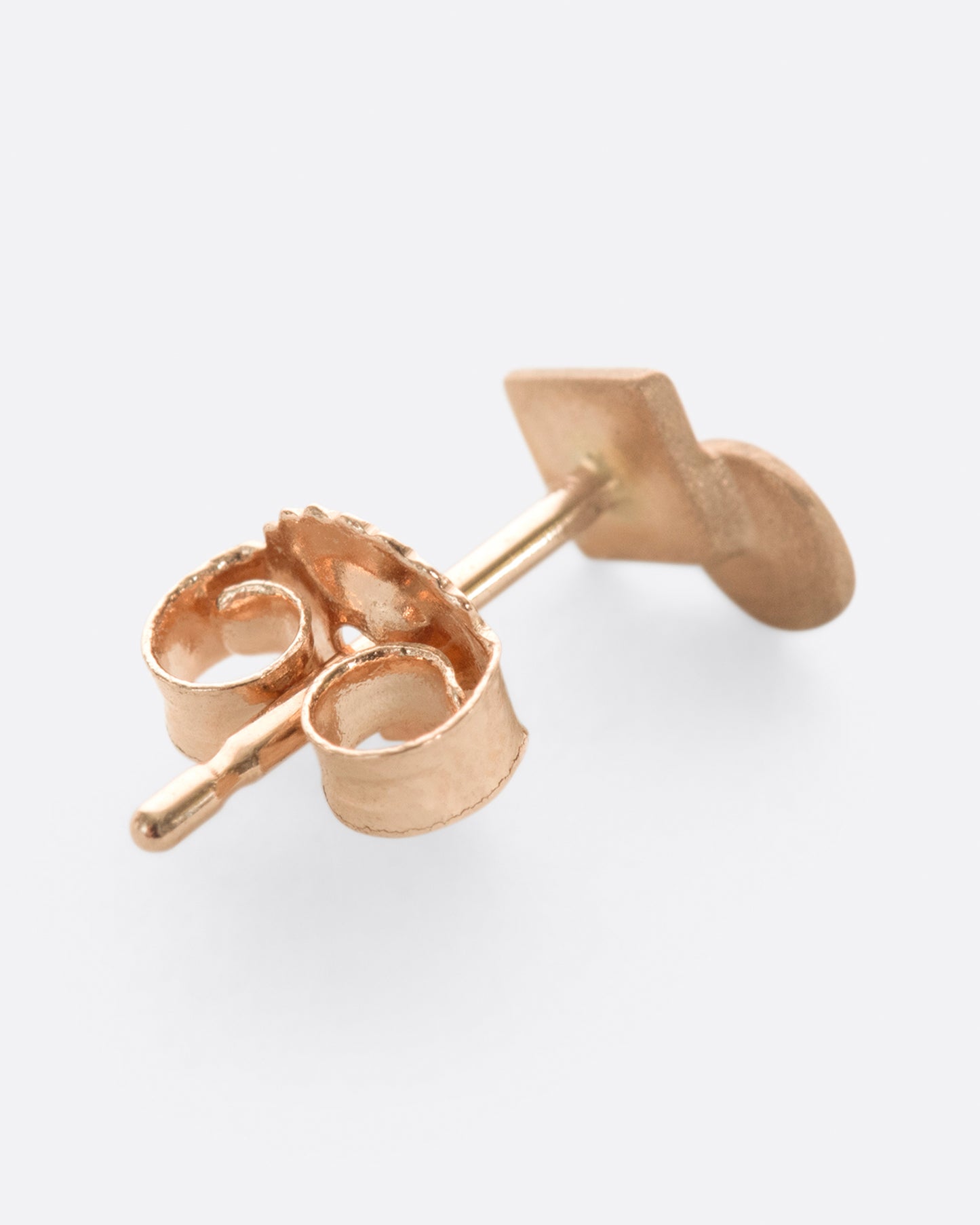A rose gold square stud earring with overlapping circle and matte finish. Shown diagonally from the back.