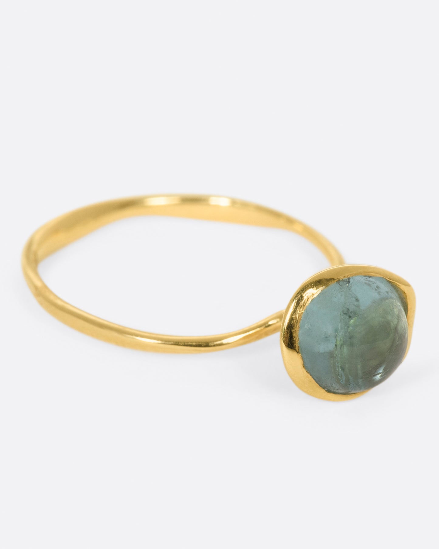 A wonky gold ring with a blue tourmaline cabochon set atop it.