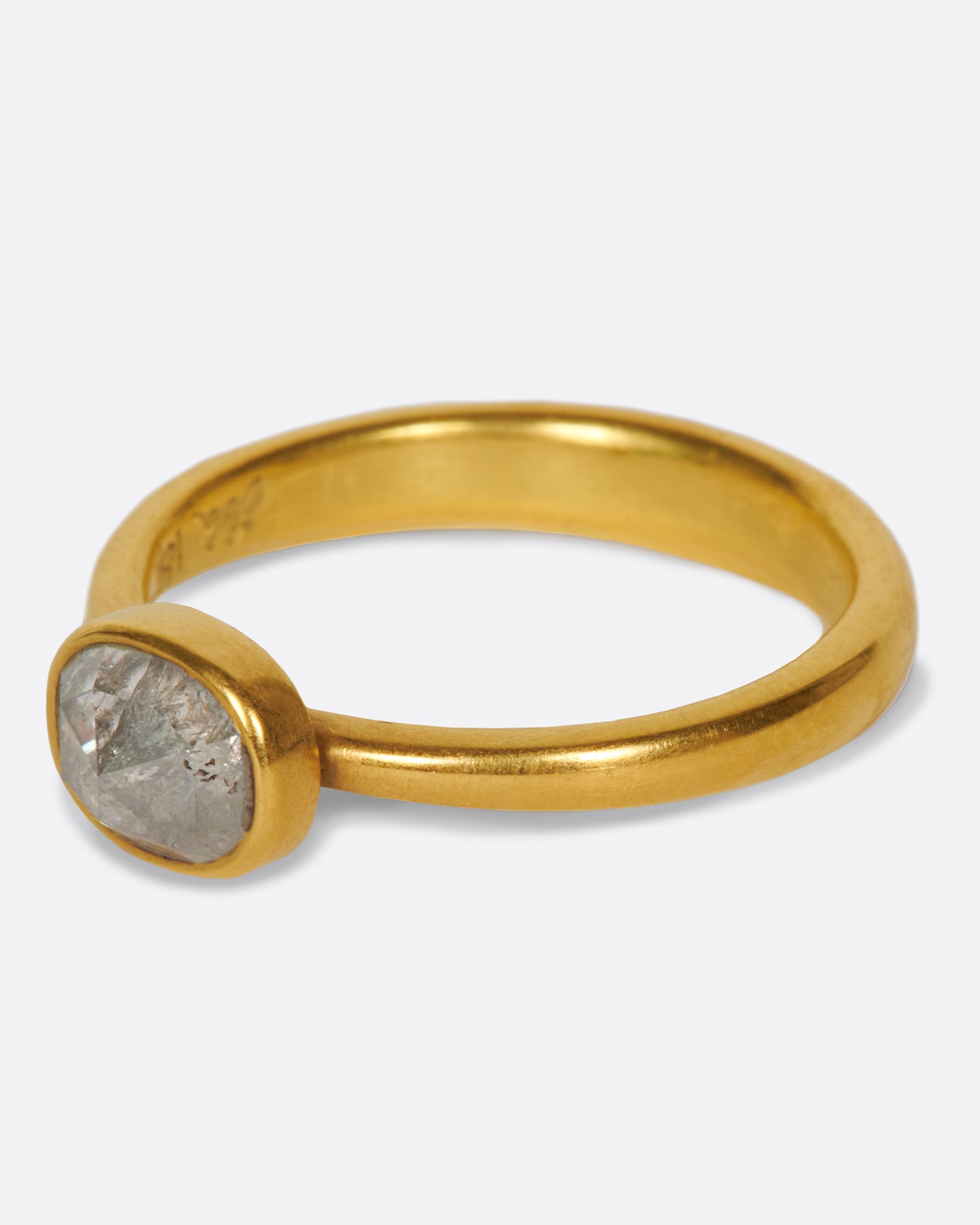 A pale grey, rose cut, oval diamond. Set horizontally on a simple, yellow gold band. Shown from the side.