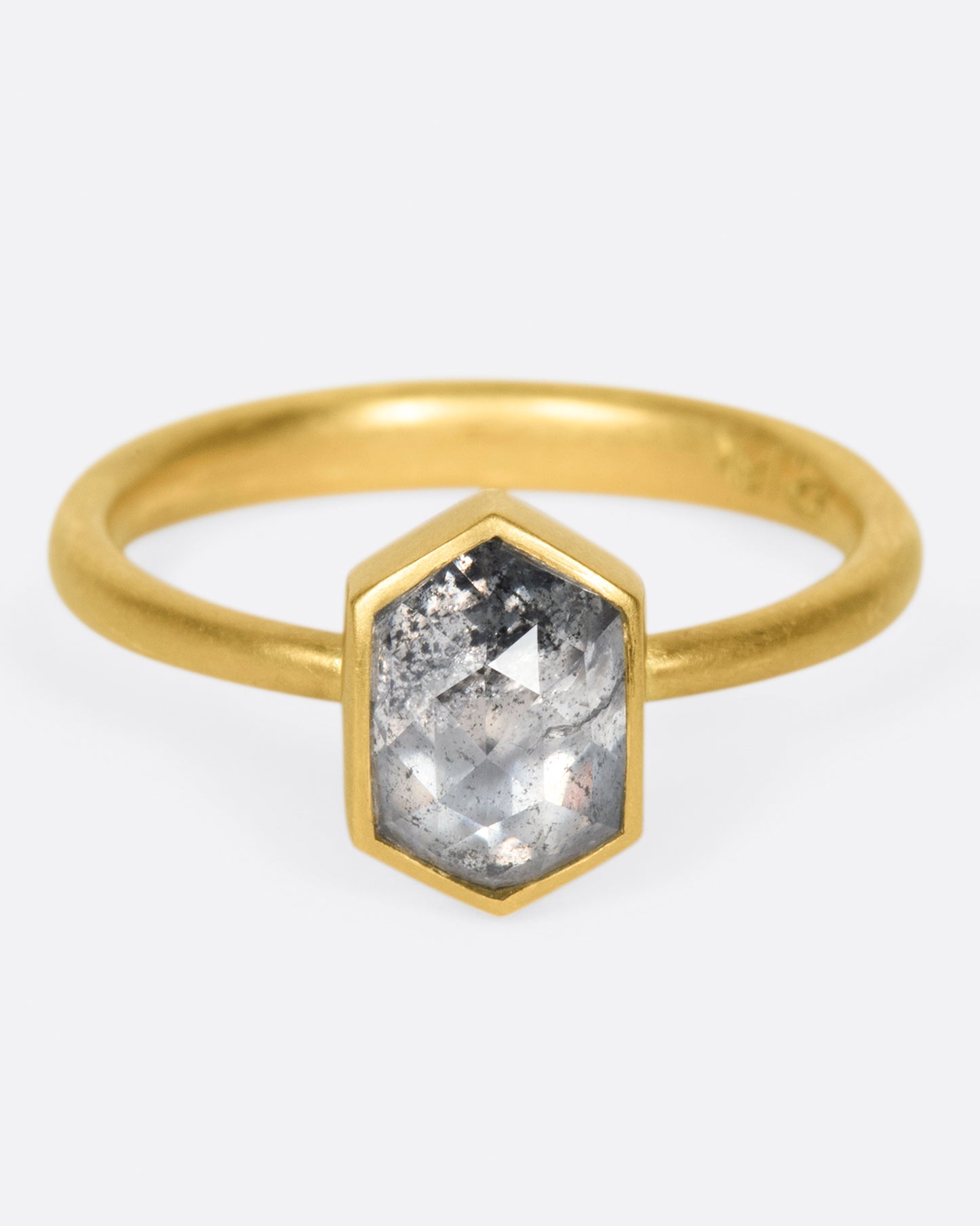 A yellow gold ring with a salt and pepper hexagonal diamond. Shown from the front.