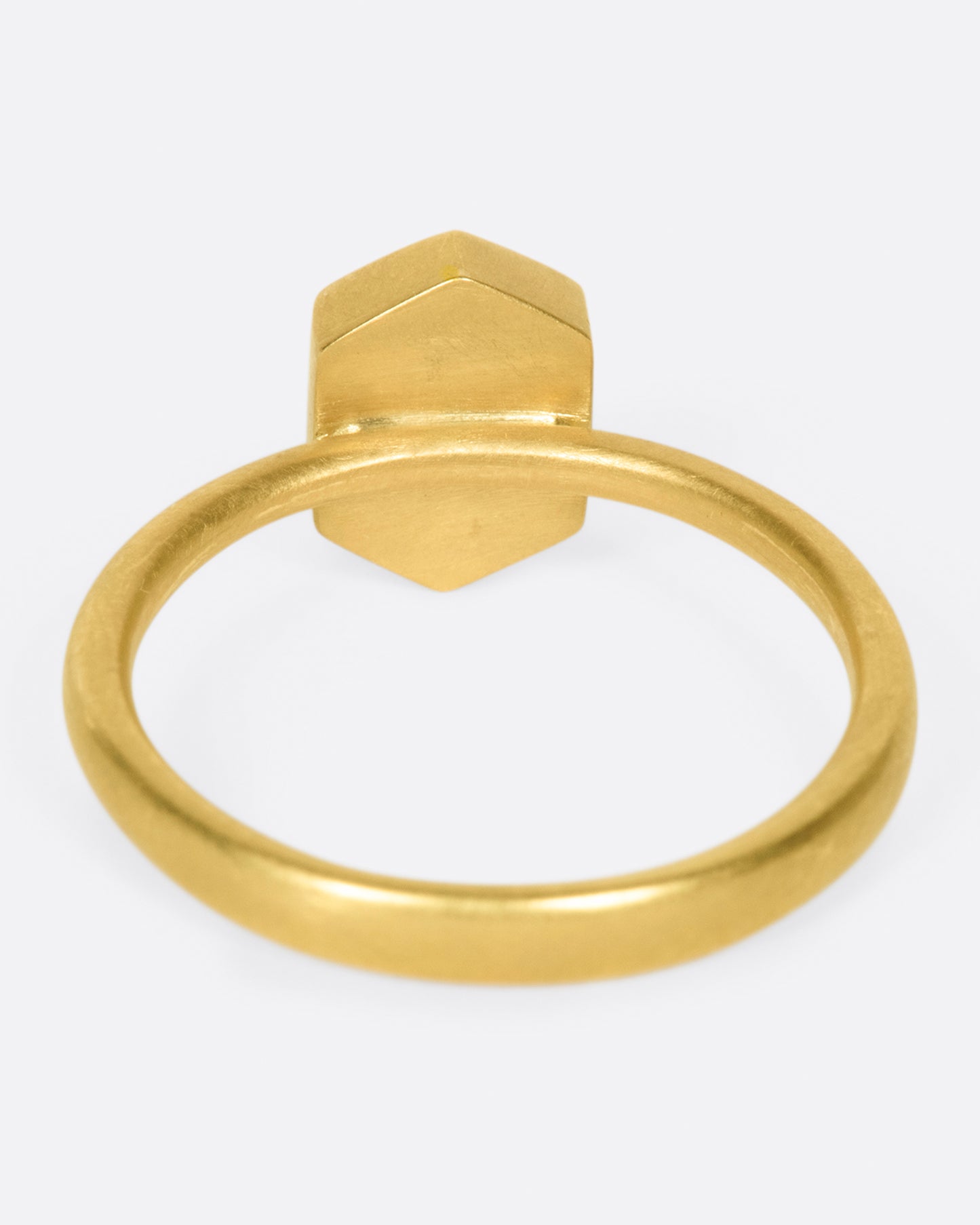 A yellow gold ring with a salt and pepper hexagonal diamond. Shown from the back.