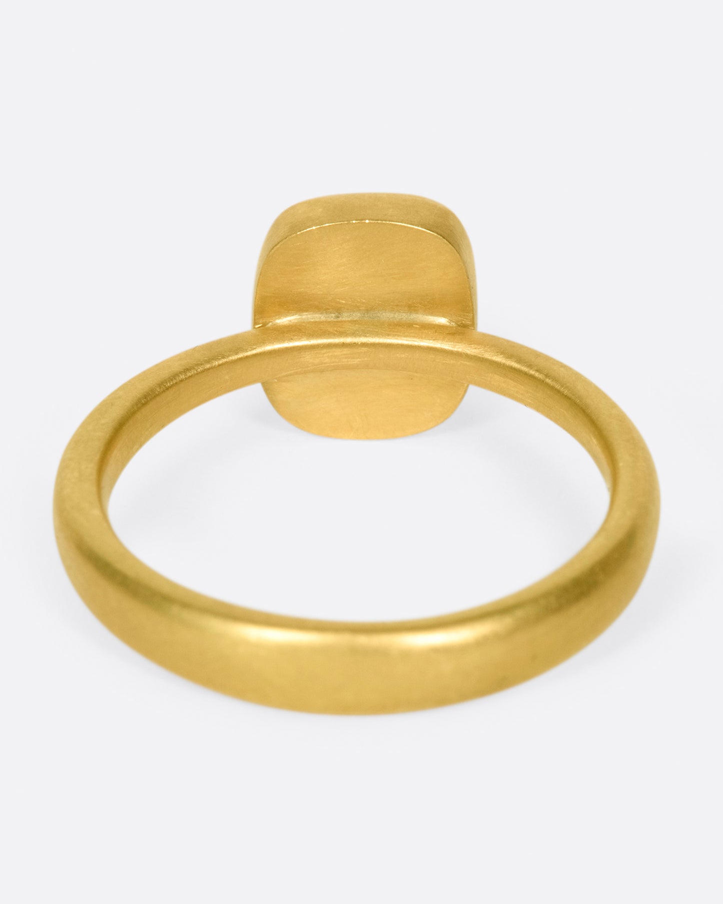 A yellow gold ring with a cushion shaped, rusty-red diamond. Shown from the back.