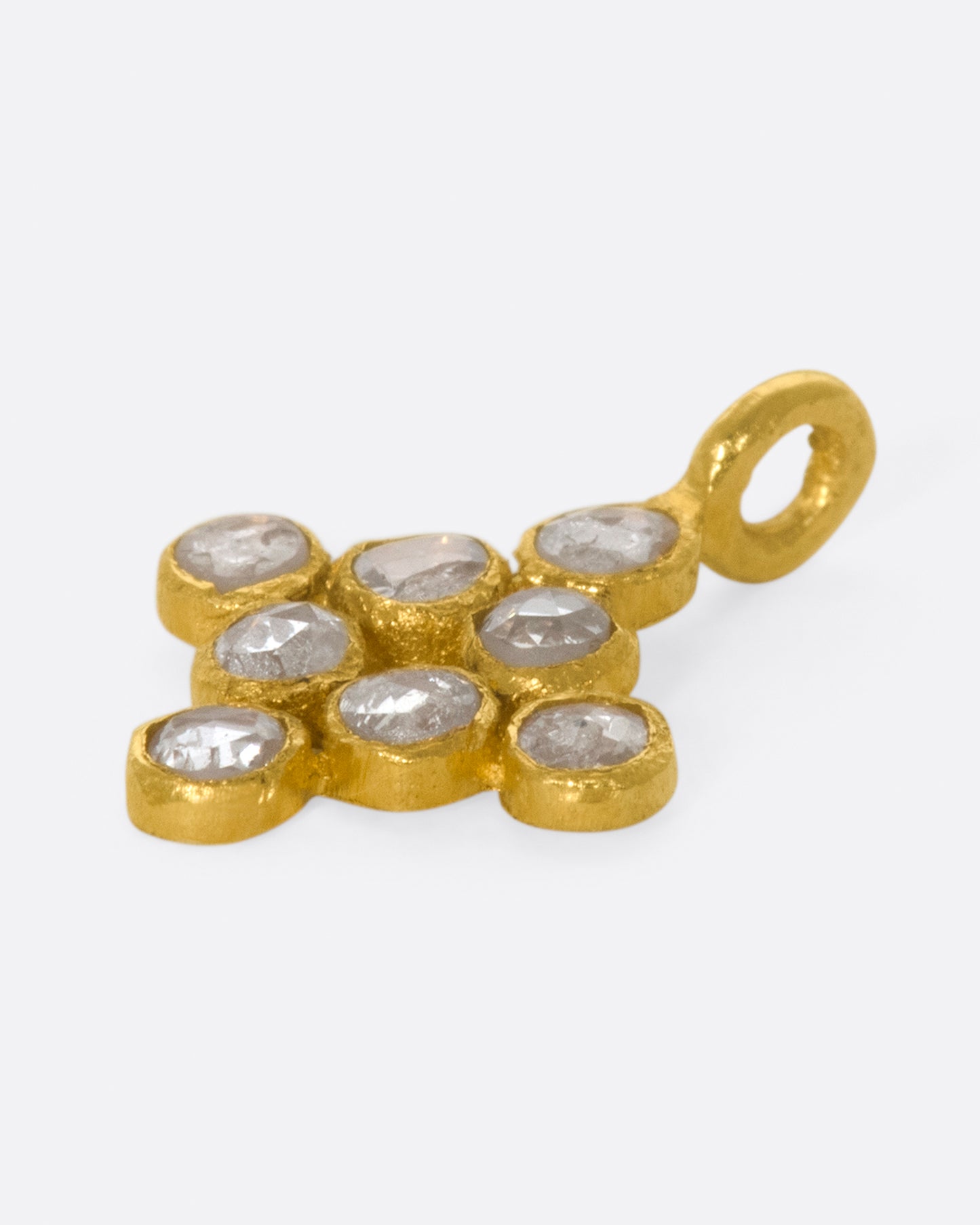 A yellow gold charm with eight rose cut diamonds set in a diamond shape. Shown lying flat from the side.