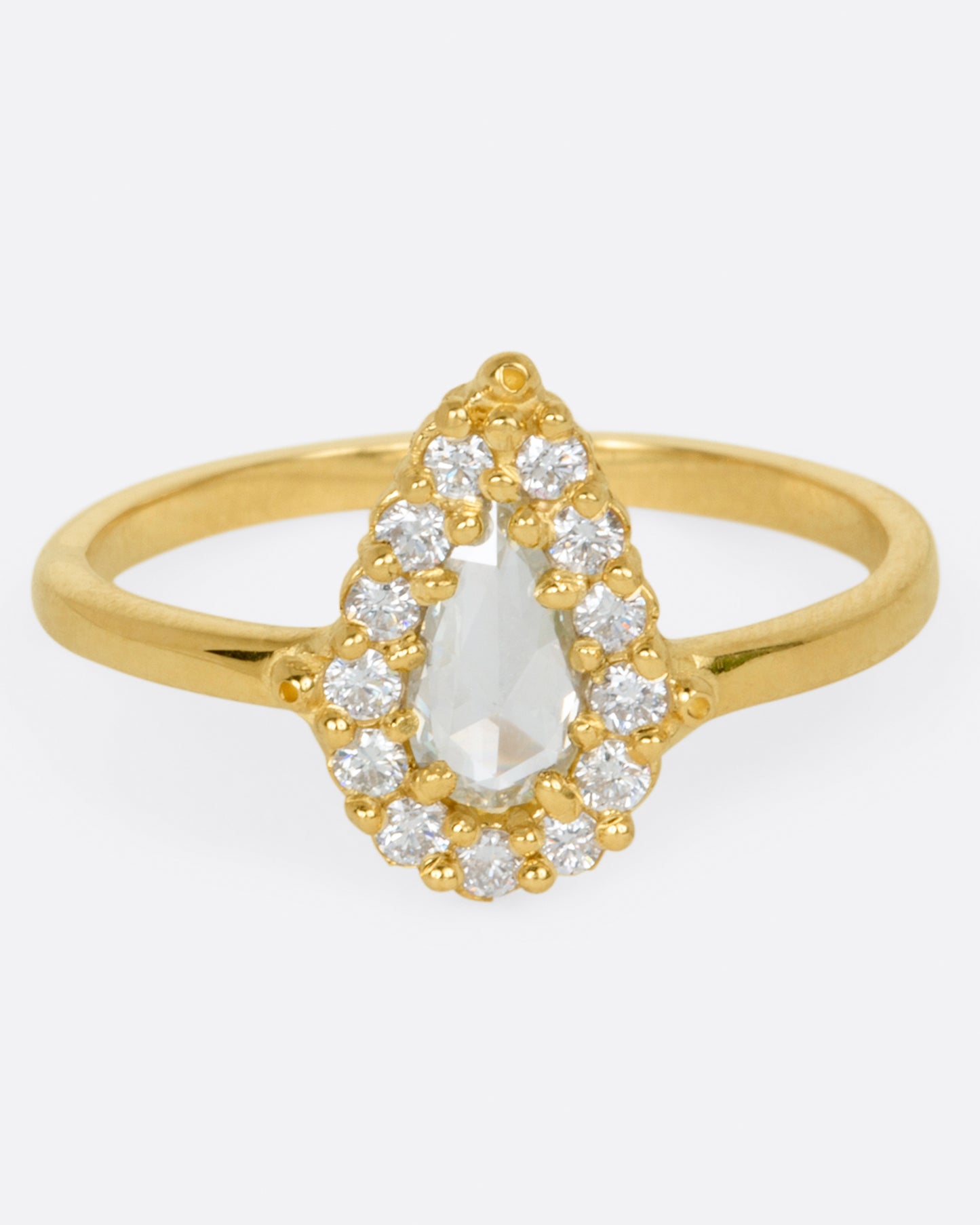 A light champagne, rose cut, pear shaped diamond ring with a round diamond halo.