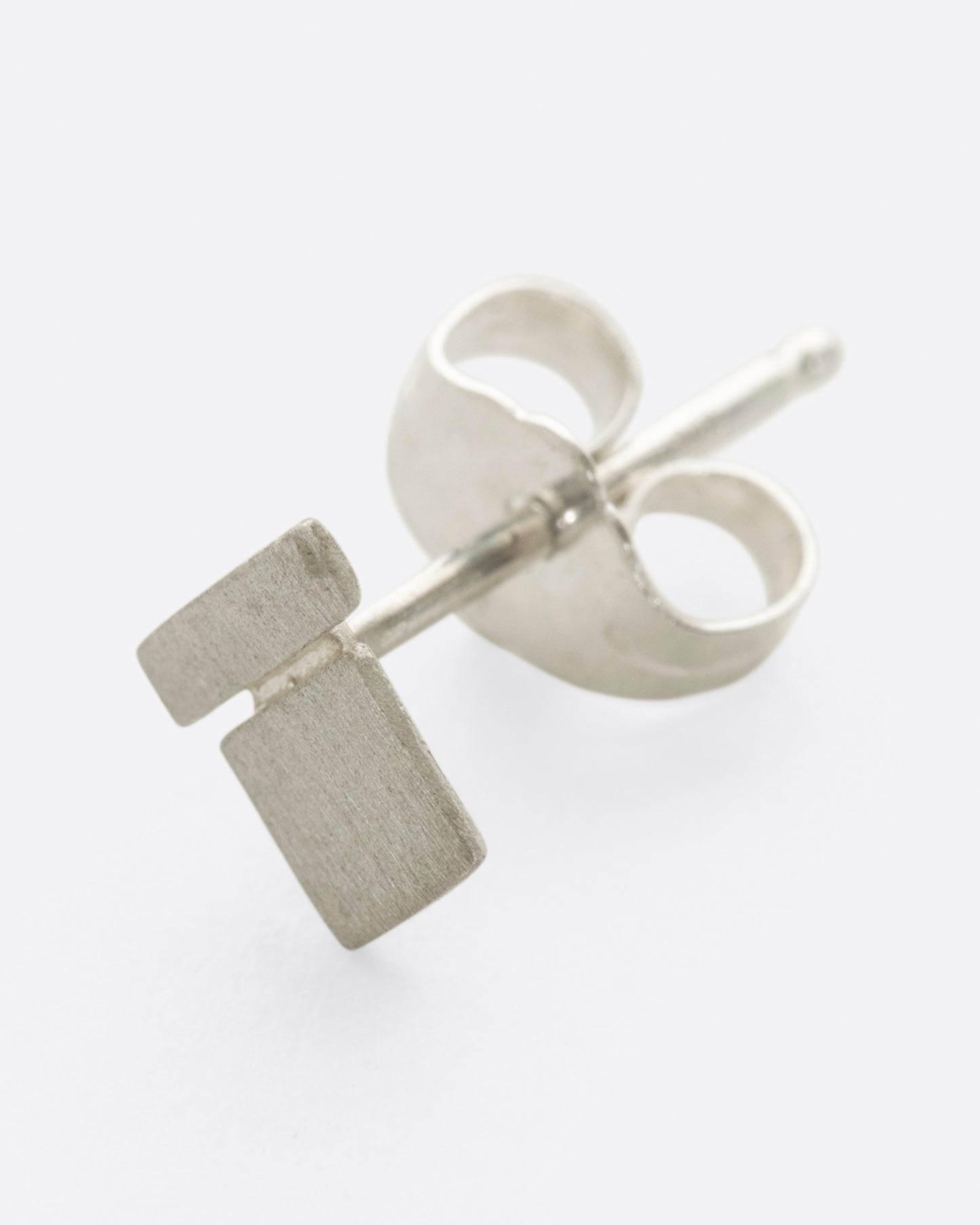A brushed sterling silver earring with a bar on a square.