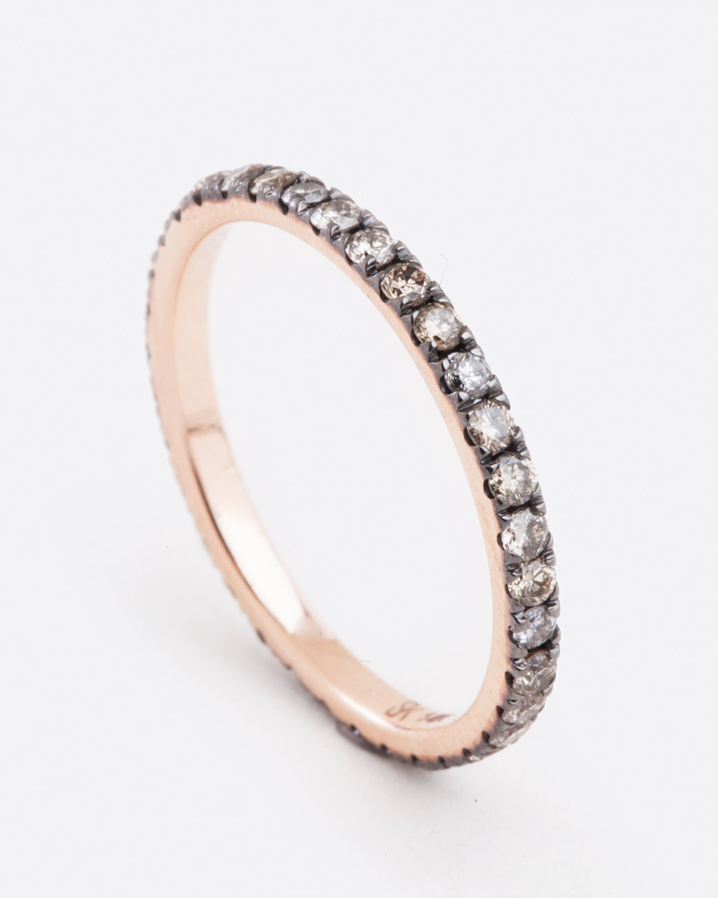 A rose gold ring with champagne and grey diamonds. Shown angled from the side.