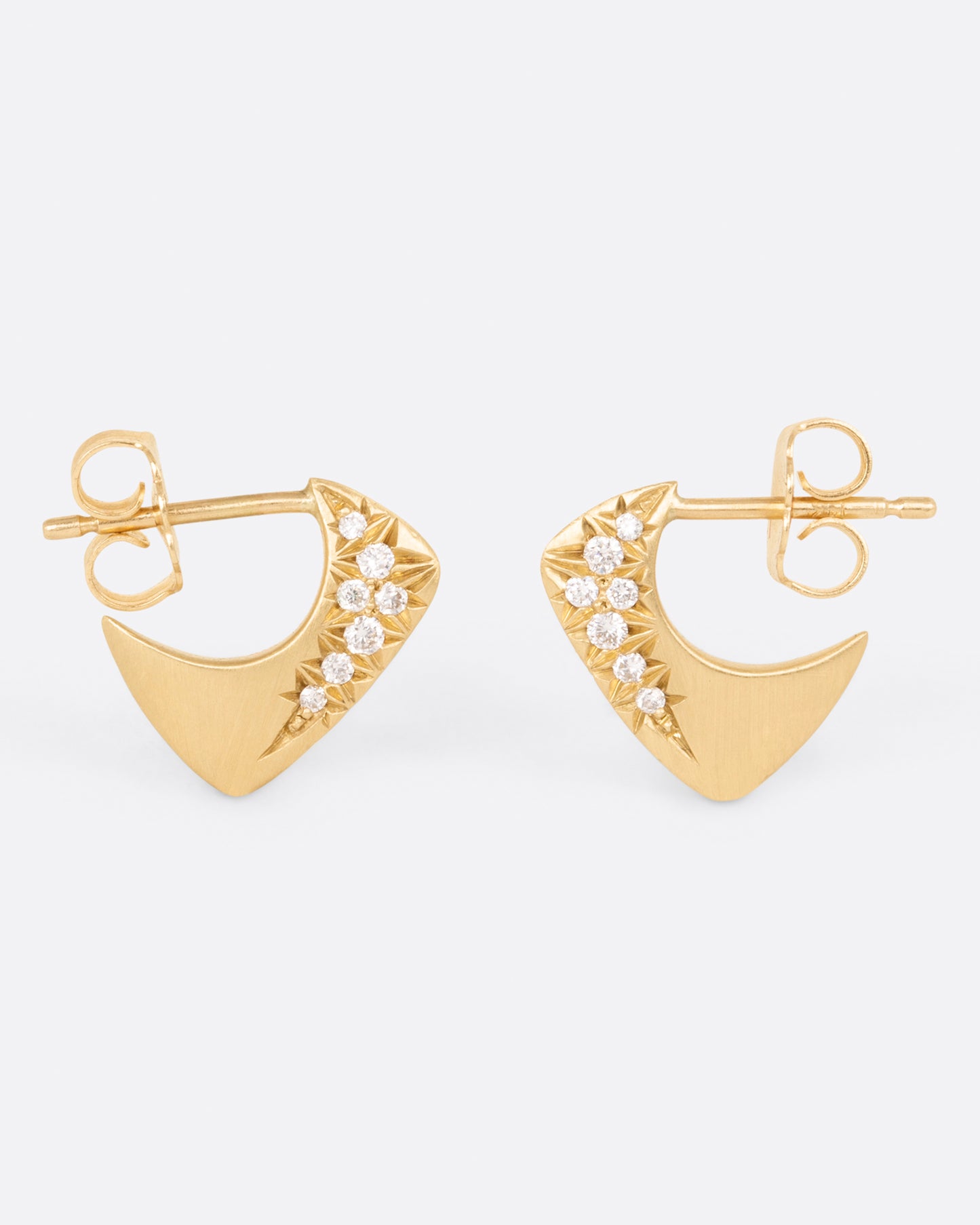 A pair of yellow gold angular huggie hoop earrings with round pave diamonds on the outside of each, shown from the side.
