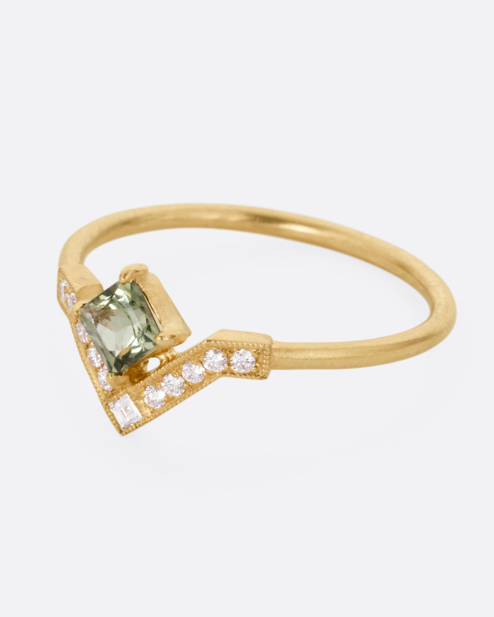 A yellow gold ring with a diamond arch and green sapphire. Shown from the side.