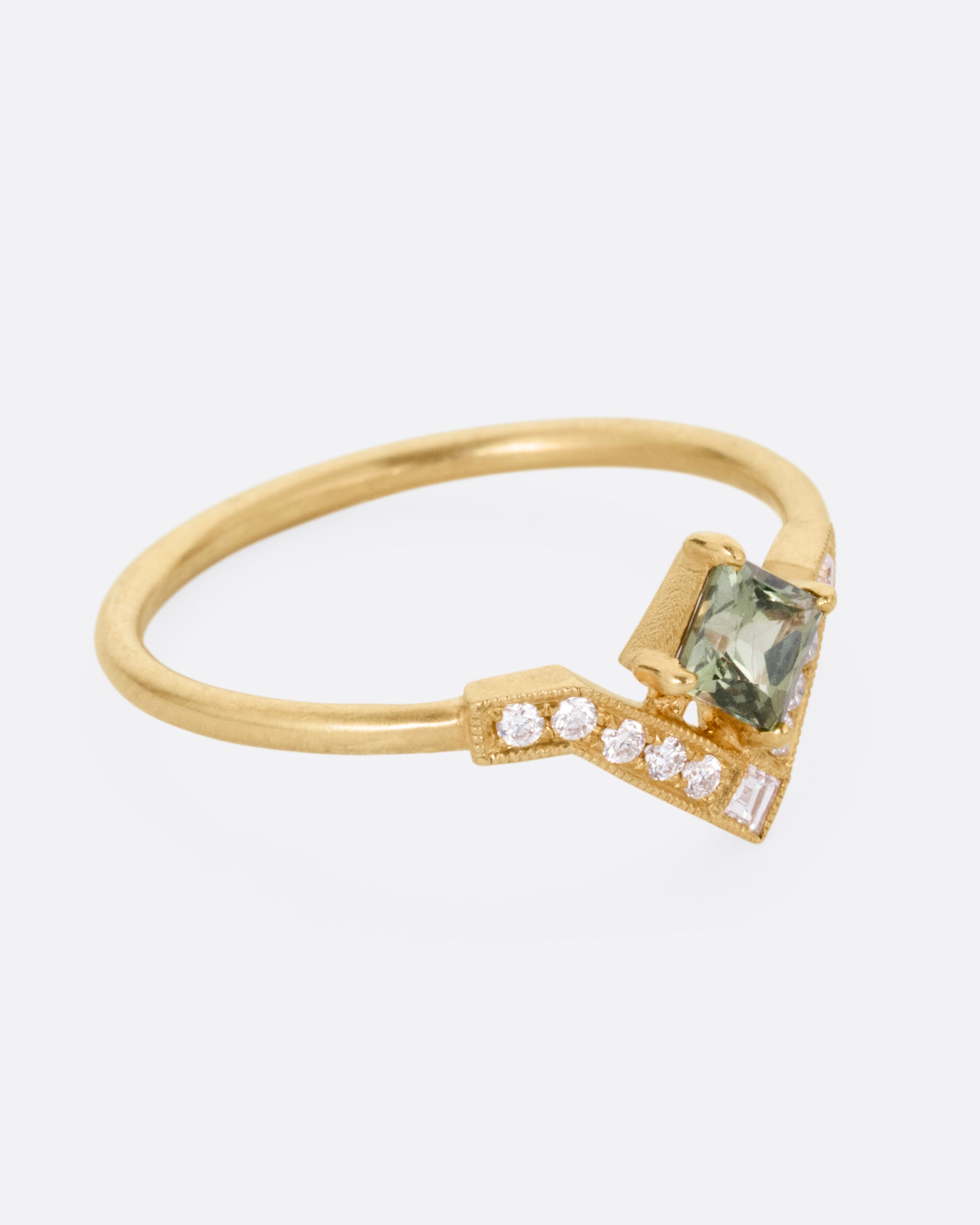 A yellow gold ring with a diamond arch and green sapphire. Shown from the side.