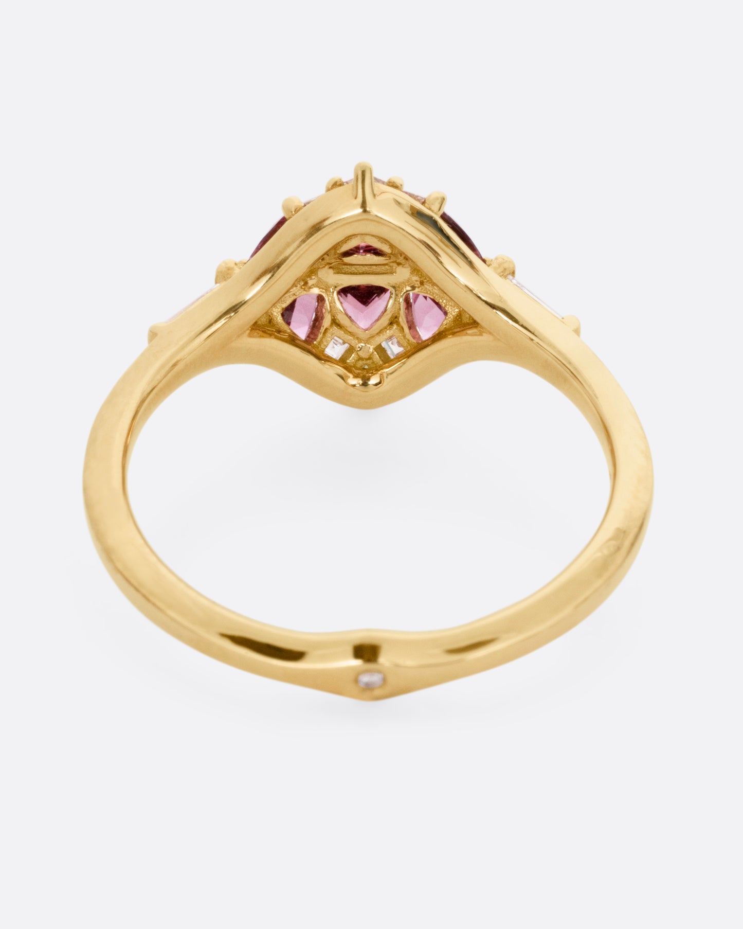 A yellow gold ring with a row of baguette diamonds passing through a cluster of trillion cut garnets and diamond accents. Shown from the back.