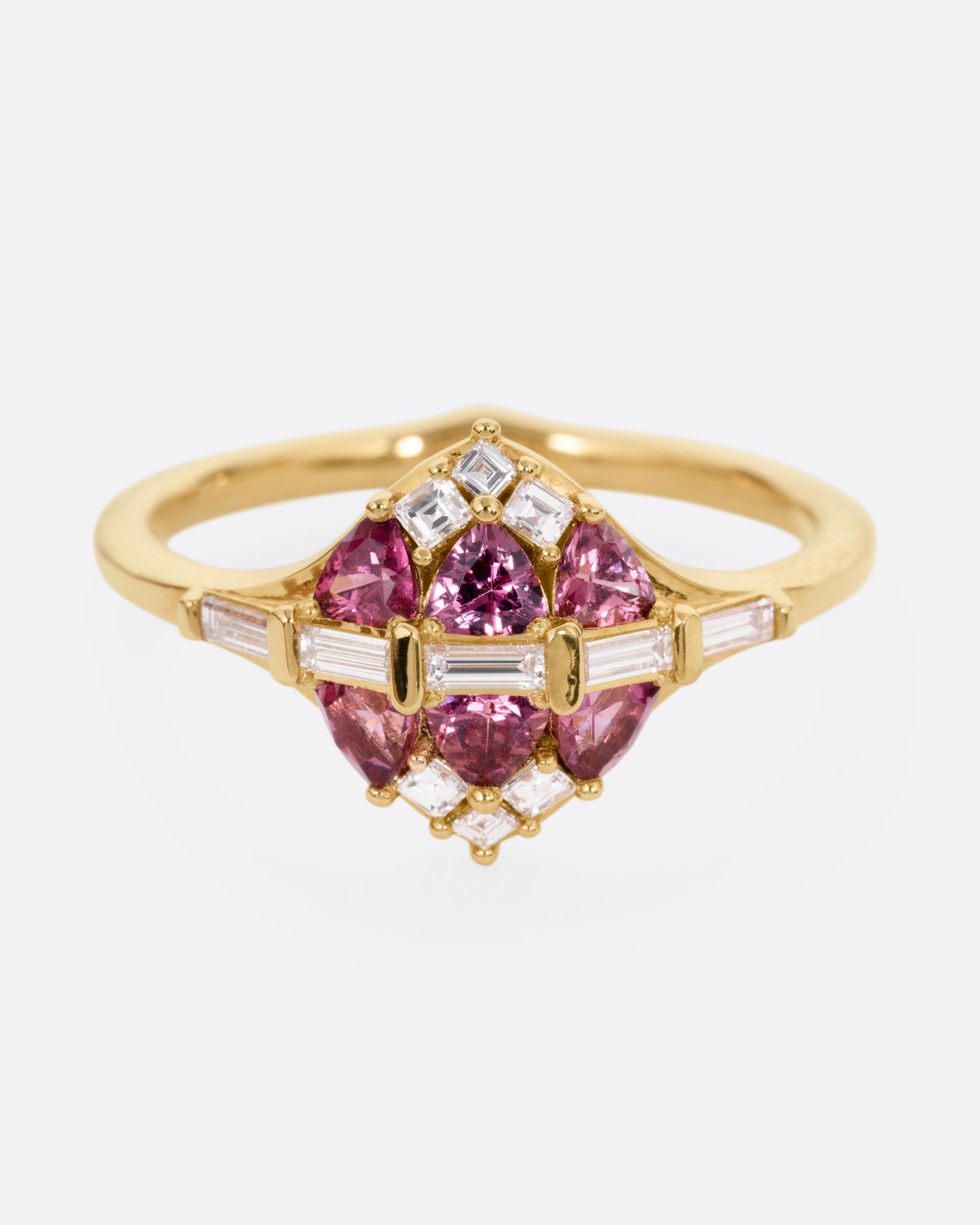 A yellow gold ring with a row of baguette diamonds passing through a cluster of trillion cut garnets and diamond accents. Shown from the front.