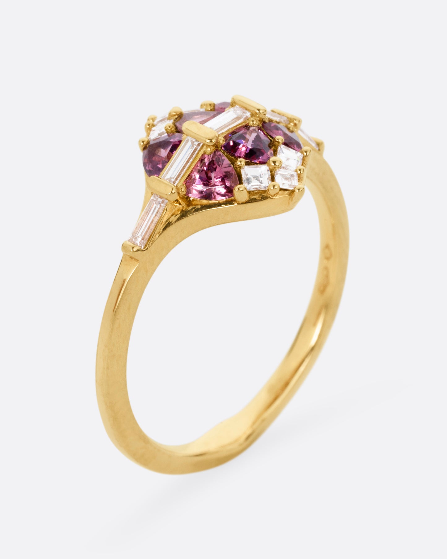 A yellow gold ring with a row of baguette diamonds passing through a cluster of trillion cut garnets and diamond accents. Shown from the side standing up.
