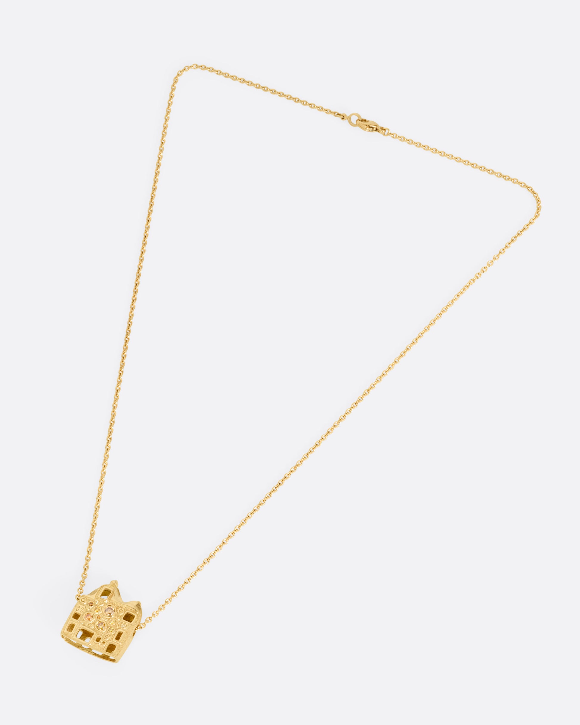 A yellow gold cable chain with a house shaped pendant with open windows and multicolored diamonds, shown from the front.