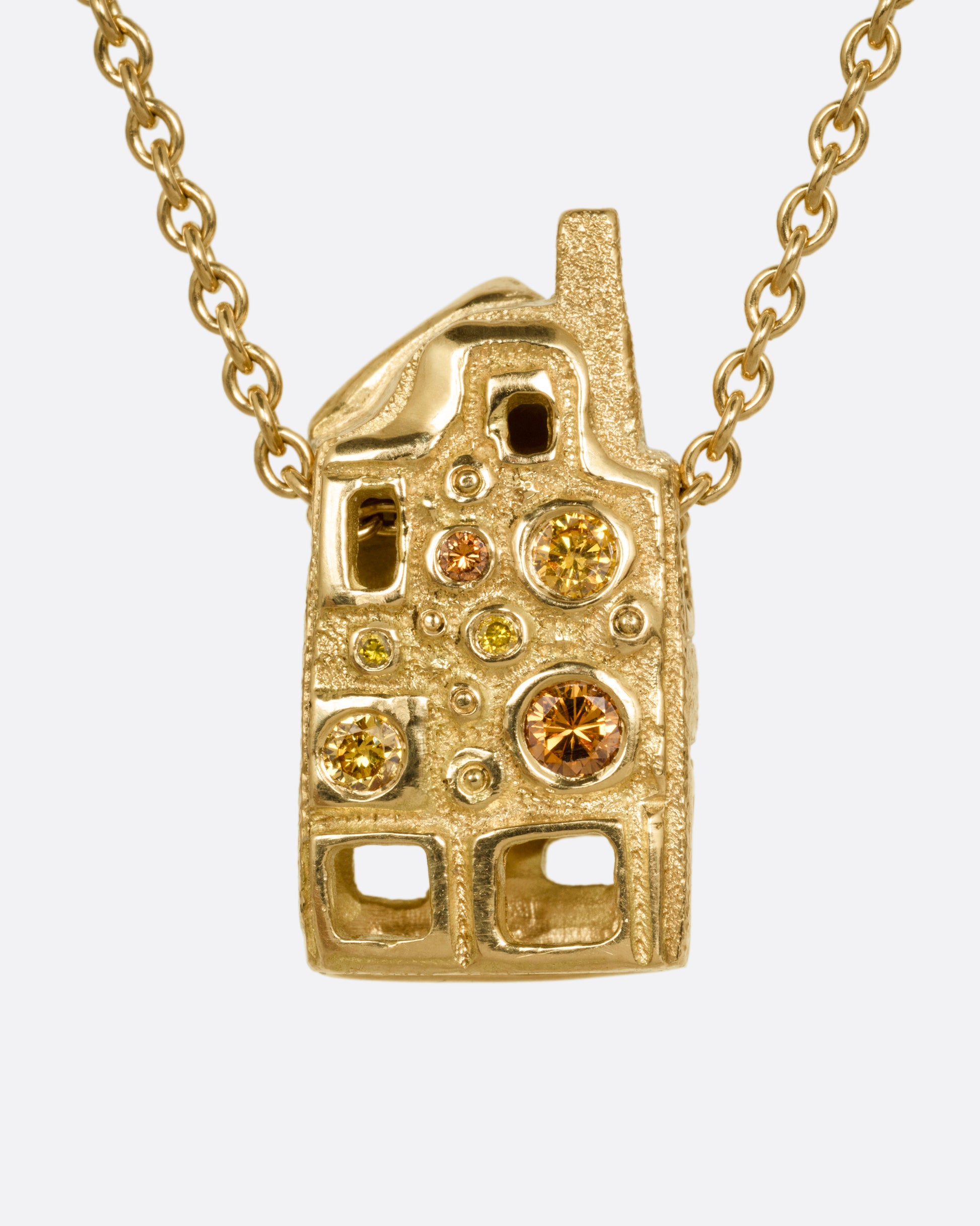 A yellow gold house-shaped pendant with multi-colored diamonds, on a cable chain, shown from the back. 