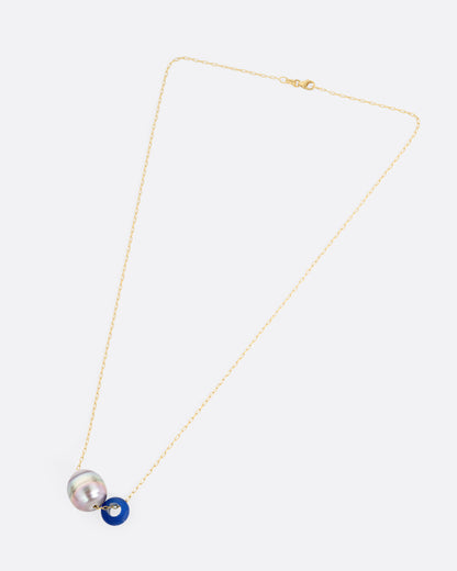 A yellow gold cable chain necklace with a blue glass antique bead and a Tahitian pearl, shown from the front.