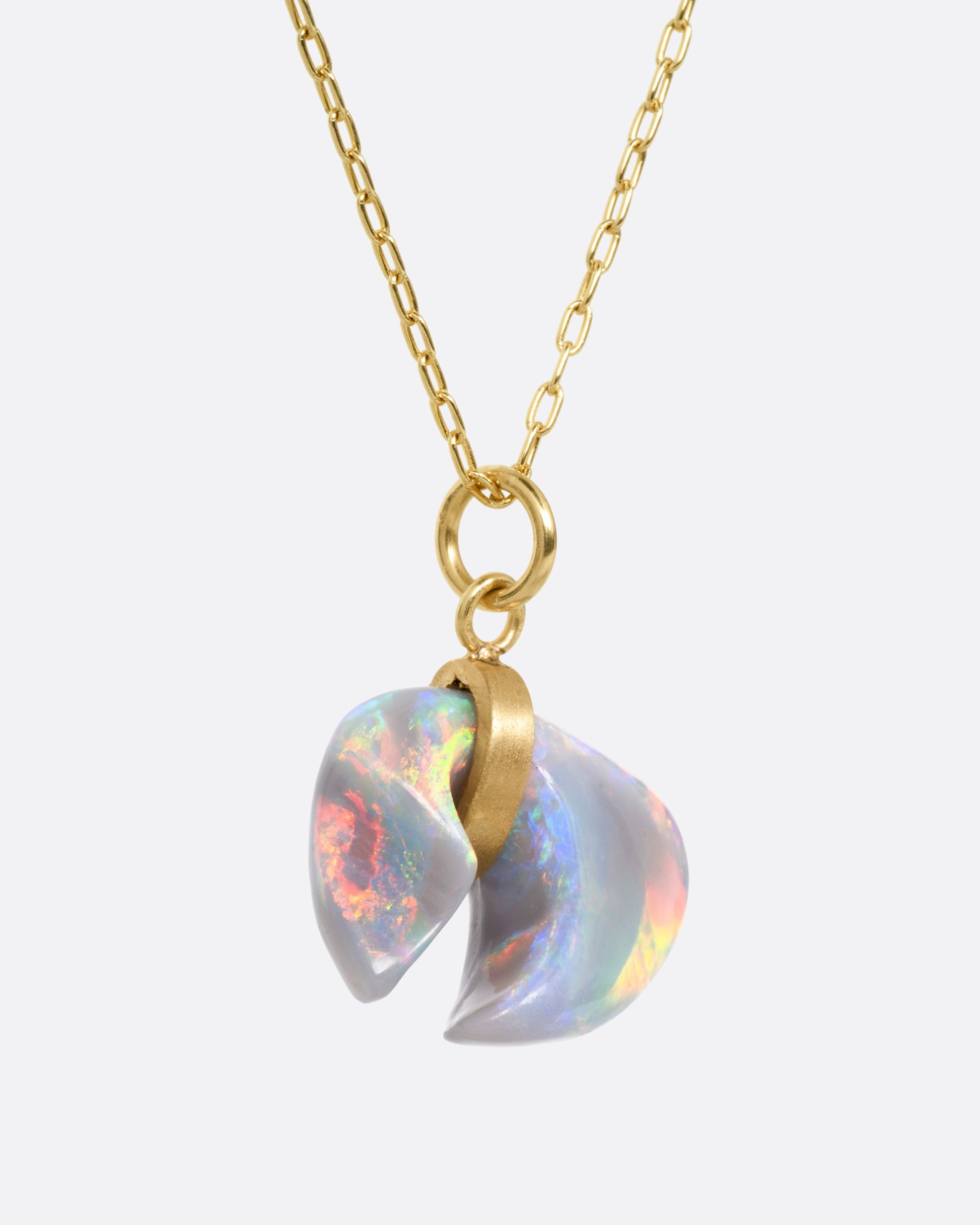 A yellow gold cable chain with a claw shaped Australian opal belted in gold, shown from the side.