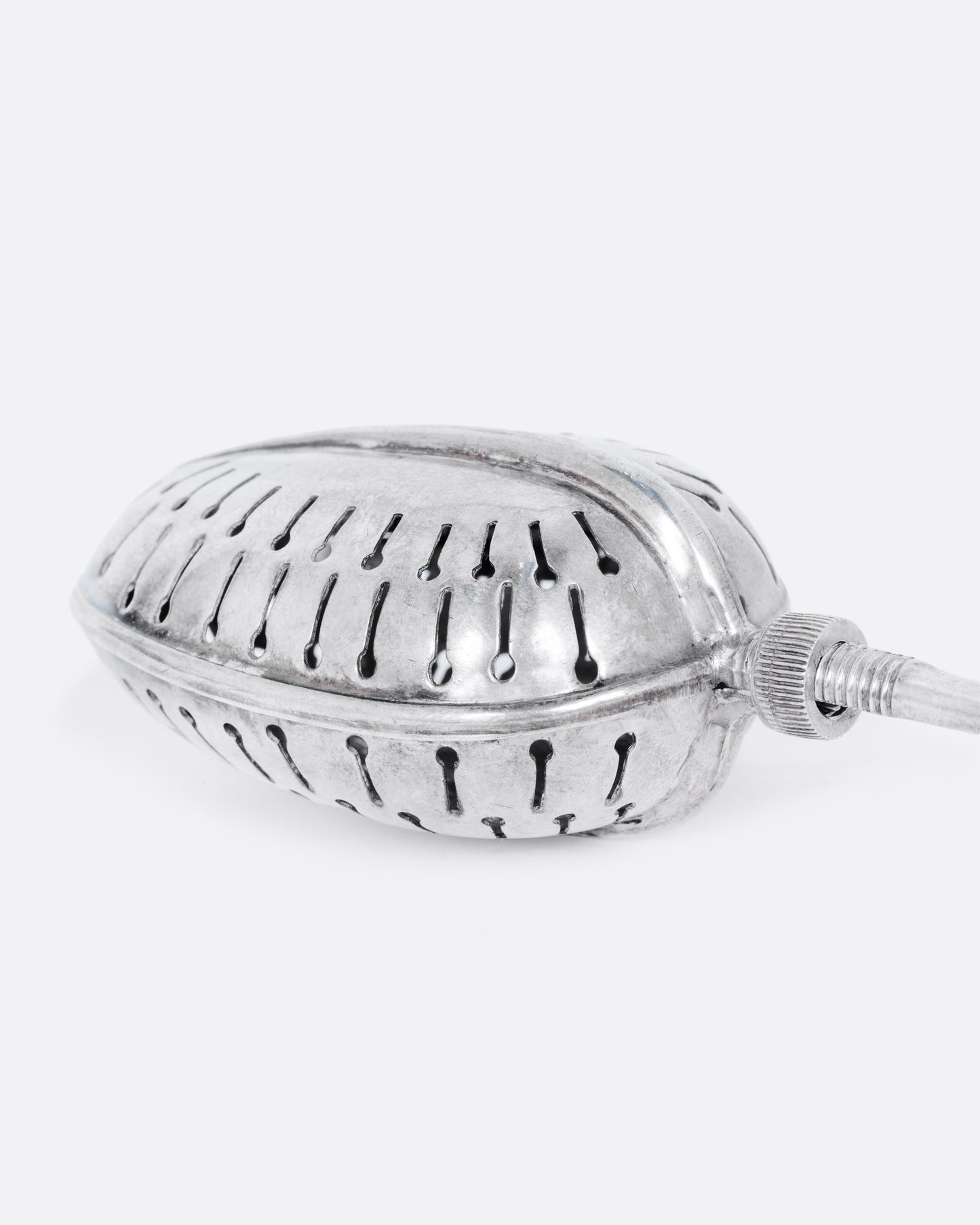 A sterling silver spoon tea infuser with a screw mechanism. Shown close up.