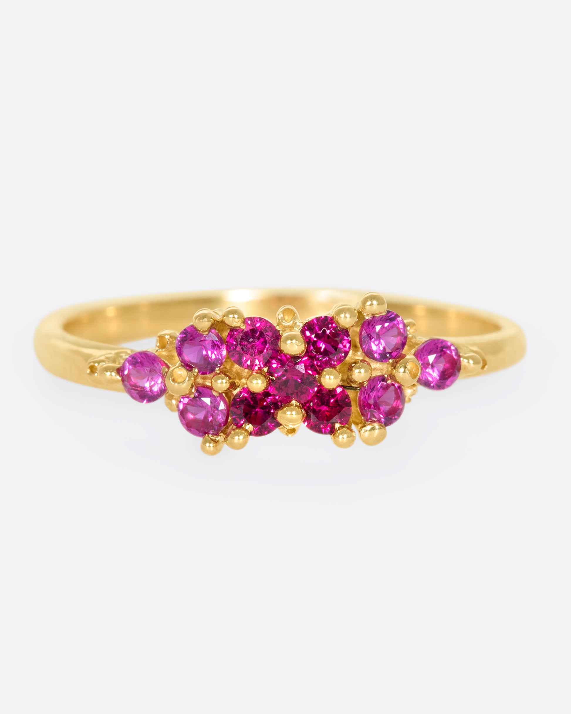 A yellow gold ring with a cluster of rubies arranged on the face. Shown from the front.