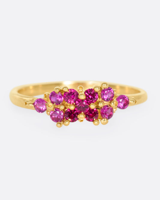 A yellow gold ring with a cluster of rubies arranged on the face. Shown from the front.