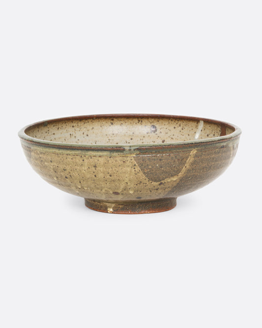 A ceramic serving bowl with a brown splattered glaze motif. Shown from the front.