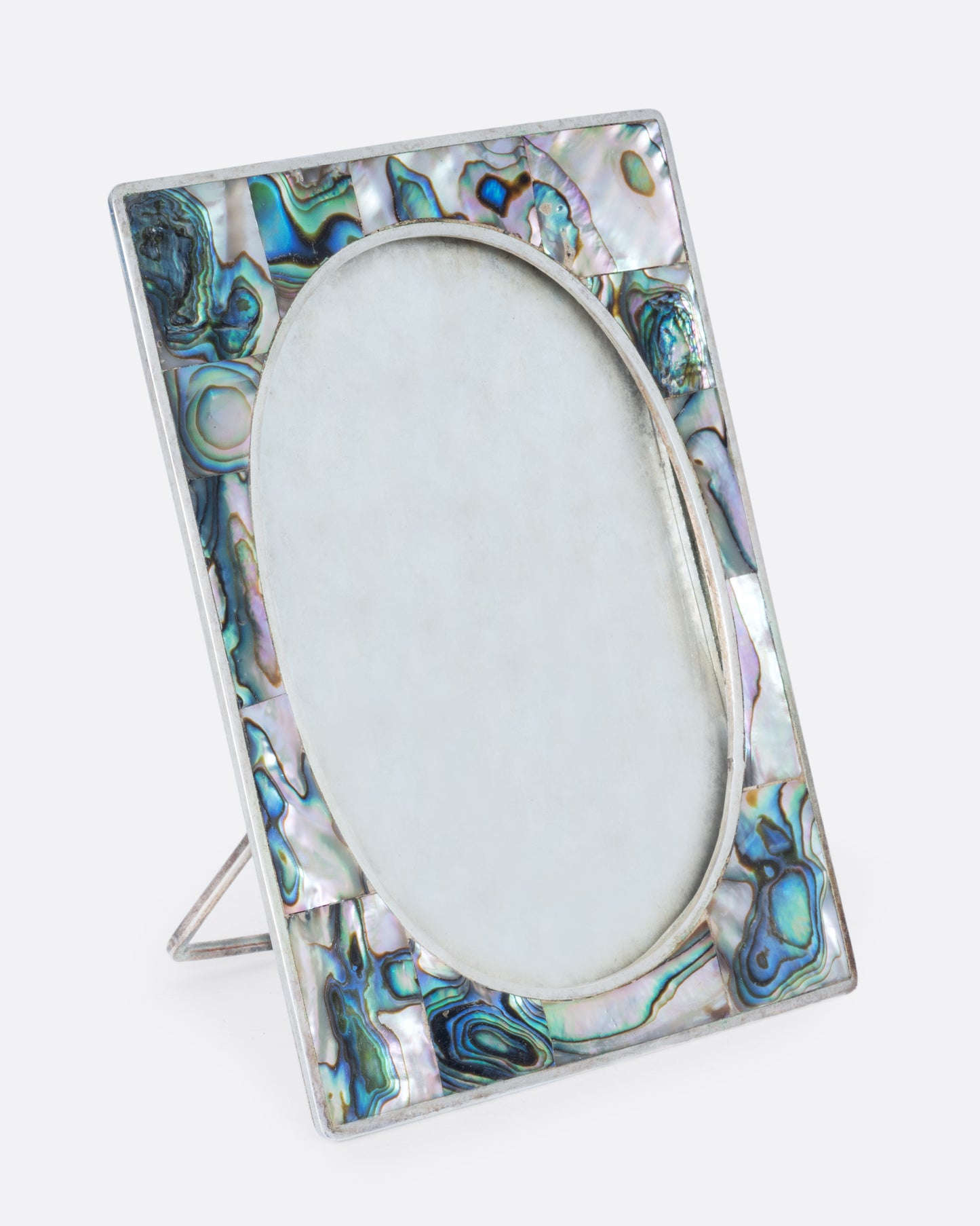 An alpaca silver oval faced frame with abalone inlay. Shown from the side.