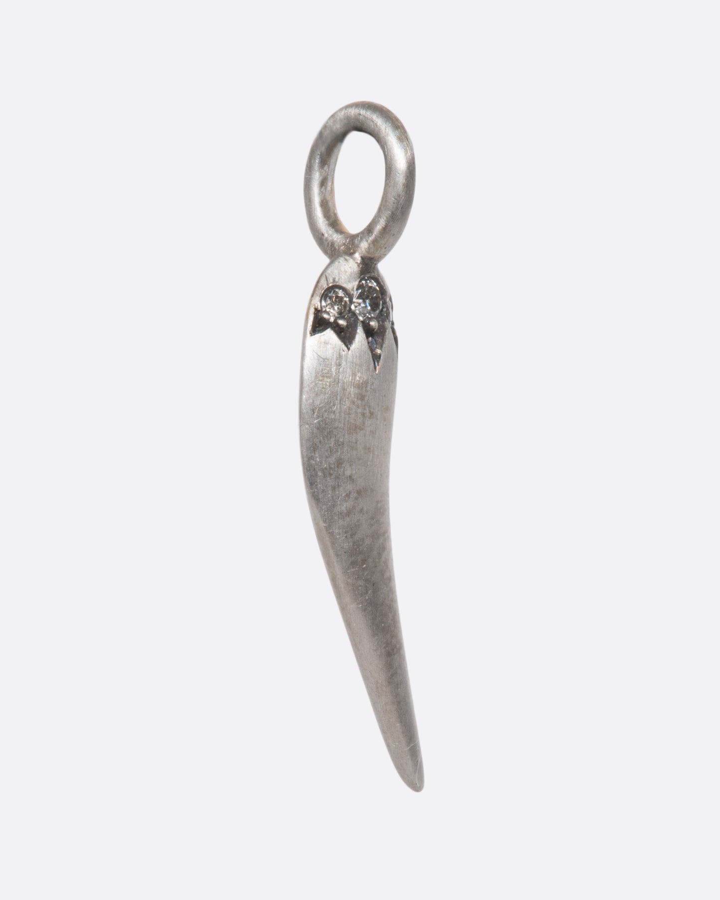 A spicy, sterling silver pepper charm with a matte finish, superbly shiny grey diamonds, and a razor thin edge. Serving sass in all the right ways.