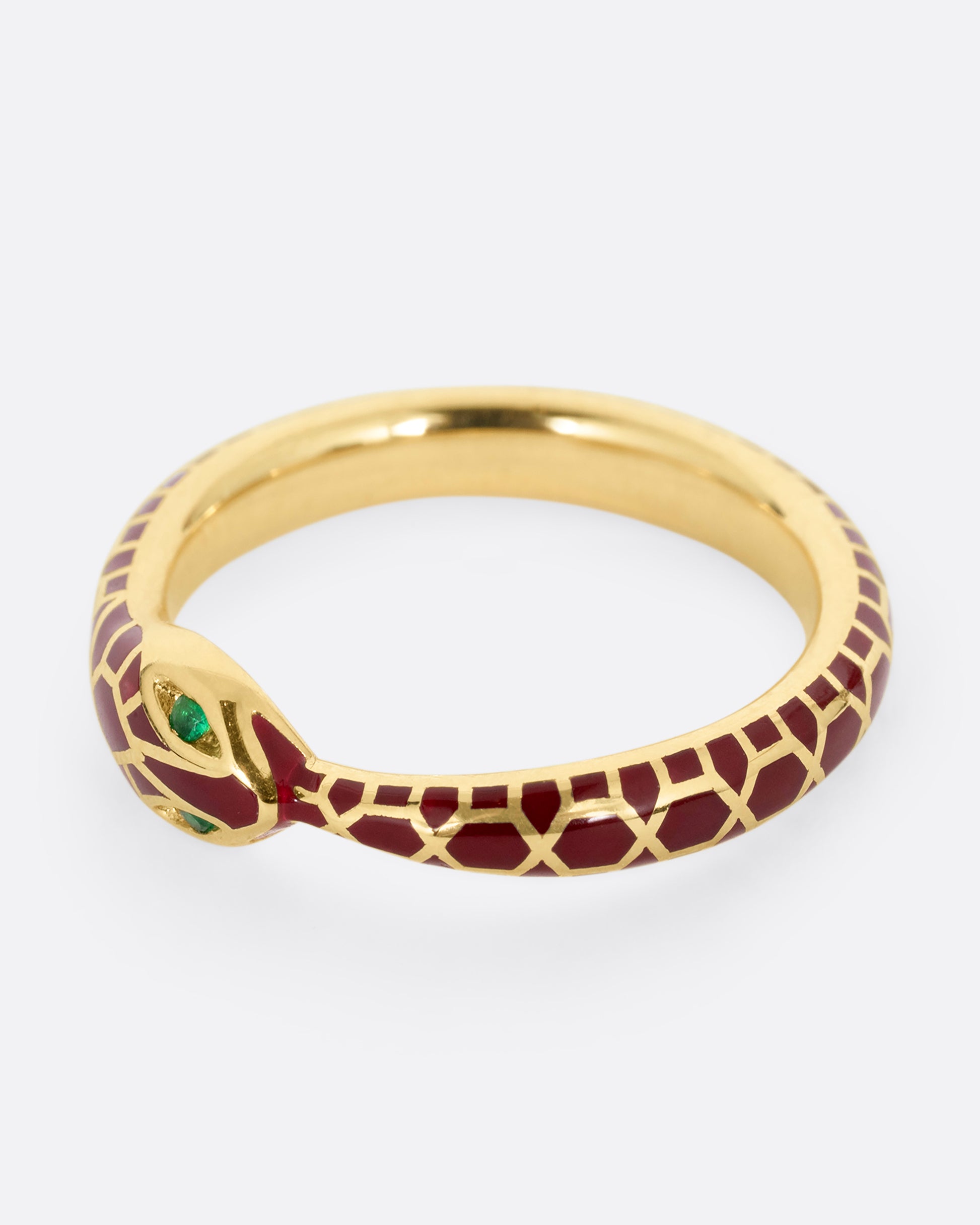 yellow gold ring with emerald and enamel shown lying flat
