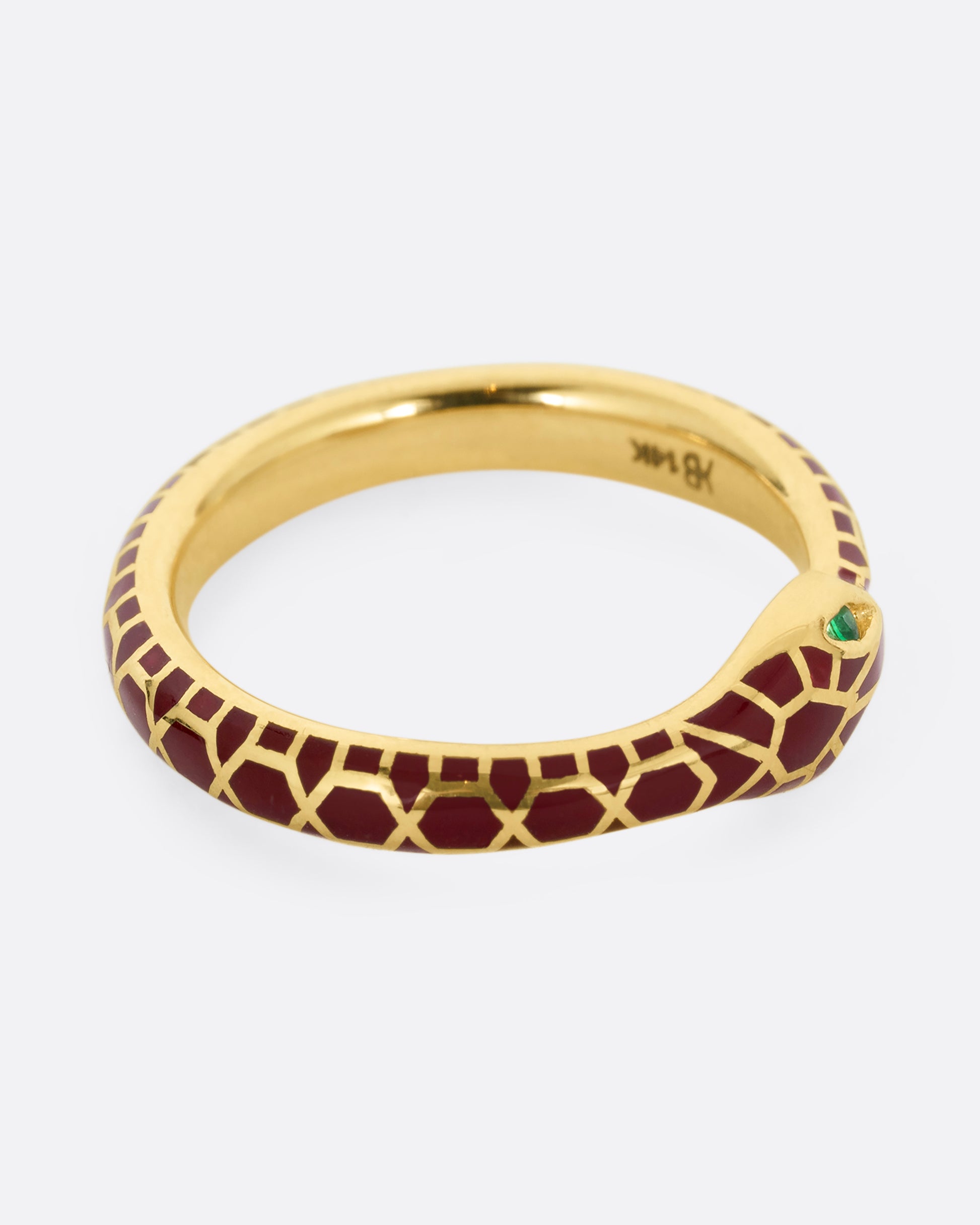yellow gold ring with emerald and enamel shown lying flat horizontally
