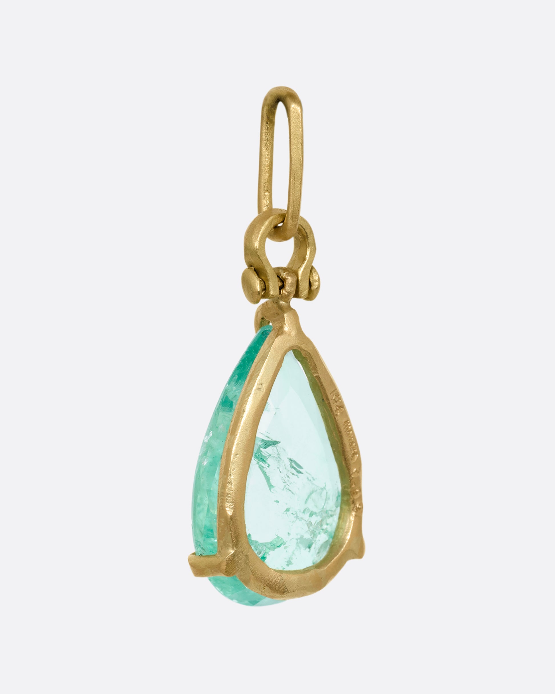 A yellow gold tear drop shaped prong set emerald pendant. Shown from the back.