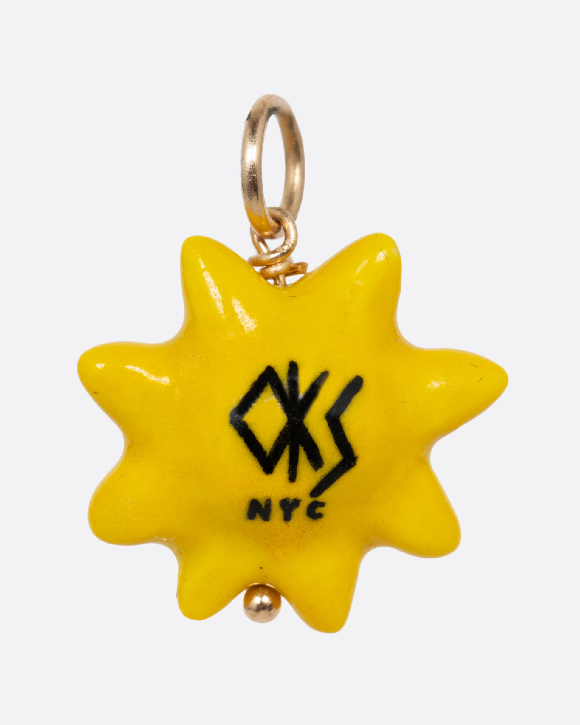 A yellow sun porcelain charm with a yellow gold bail. Shown from the back.