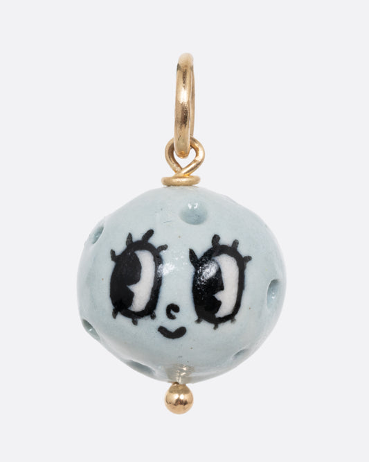 A blue full moon porcelain charm with a yellow gold bail. Shown from the front.