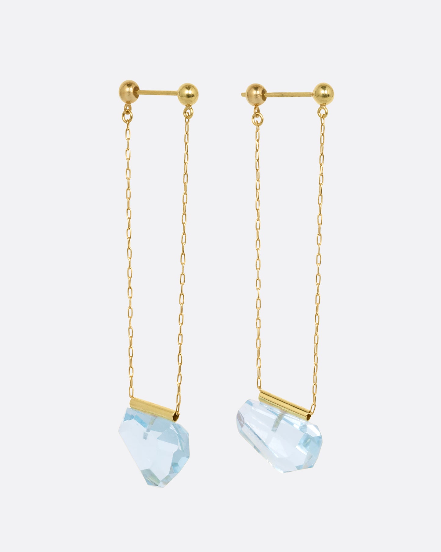 A pair of yellow gold chain earrings with free form blue topaz. Shown from the side.