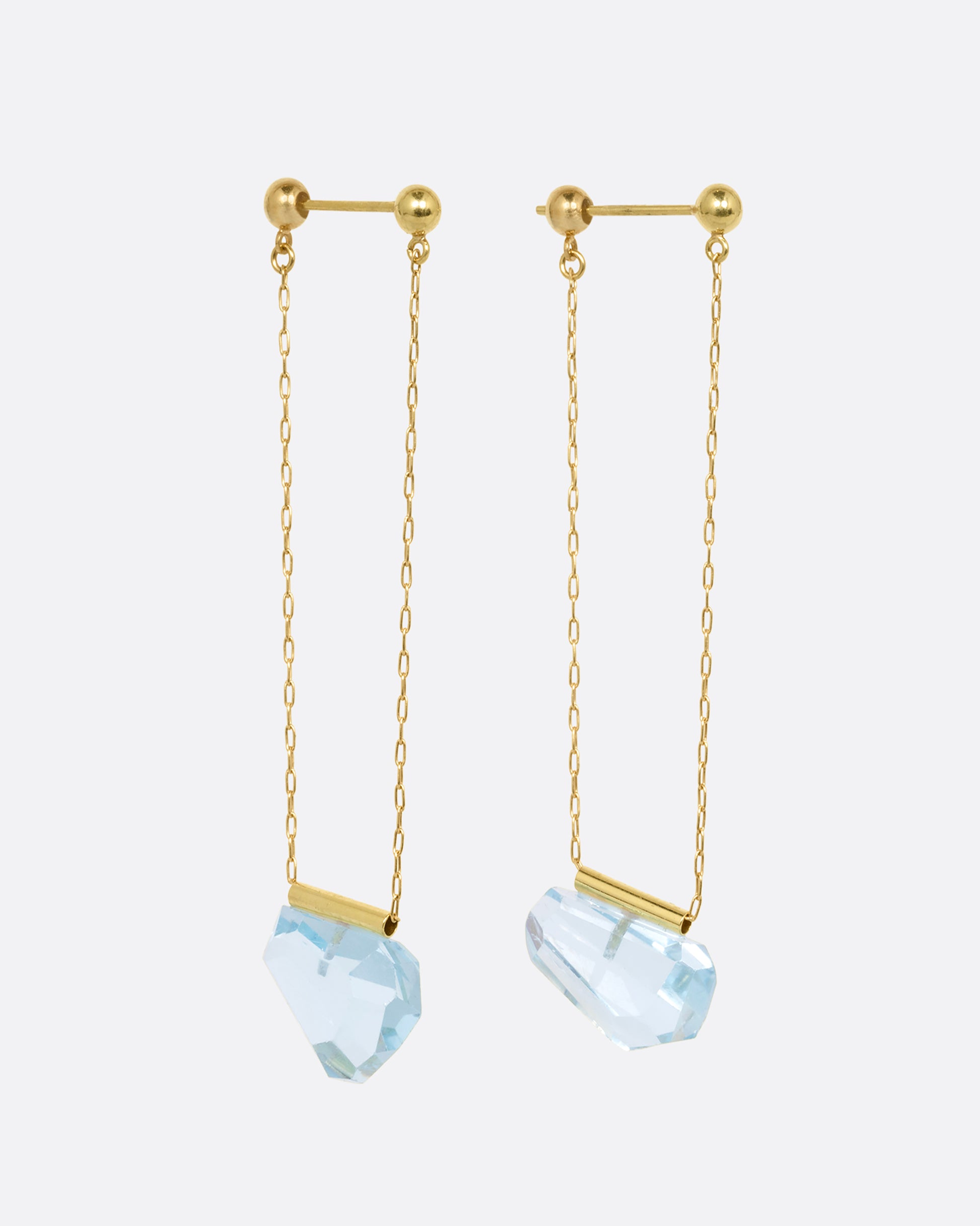 A pair of yellow gold chain earrings with free form blue topaz. Shown from the side.