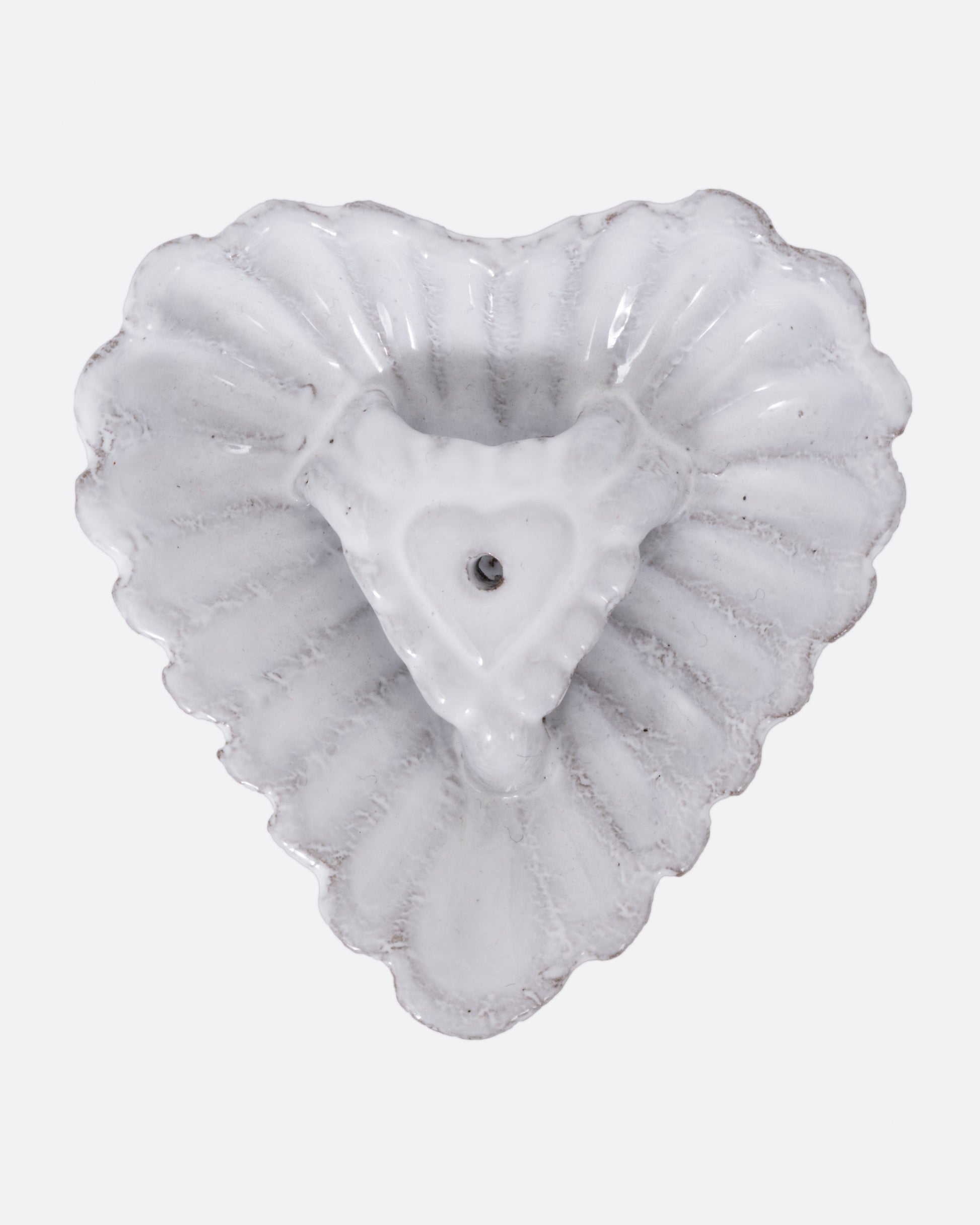 A white heart shaped incense holder, shown from the top.